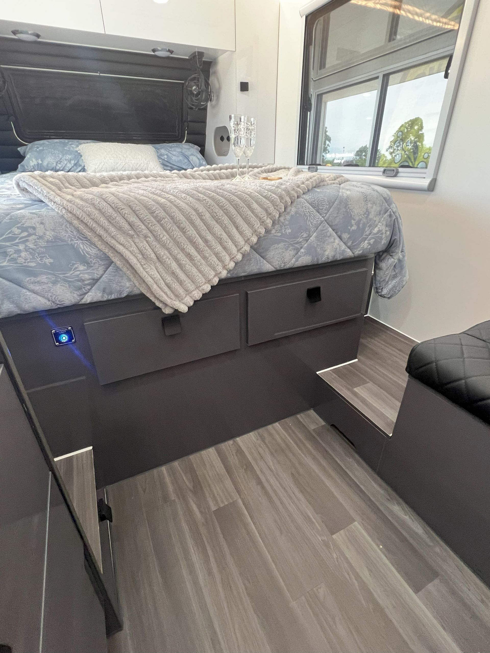 A bedroom in a camper with a bed and a window.