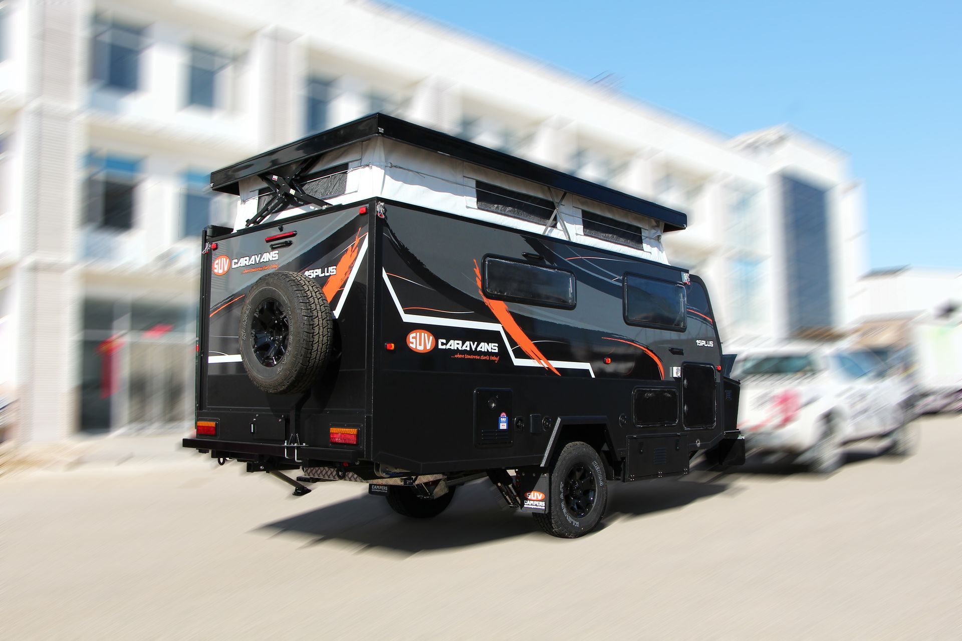 A black trailer is parked in front of a building.