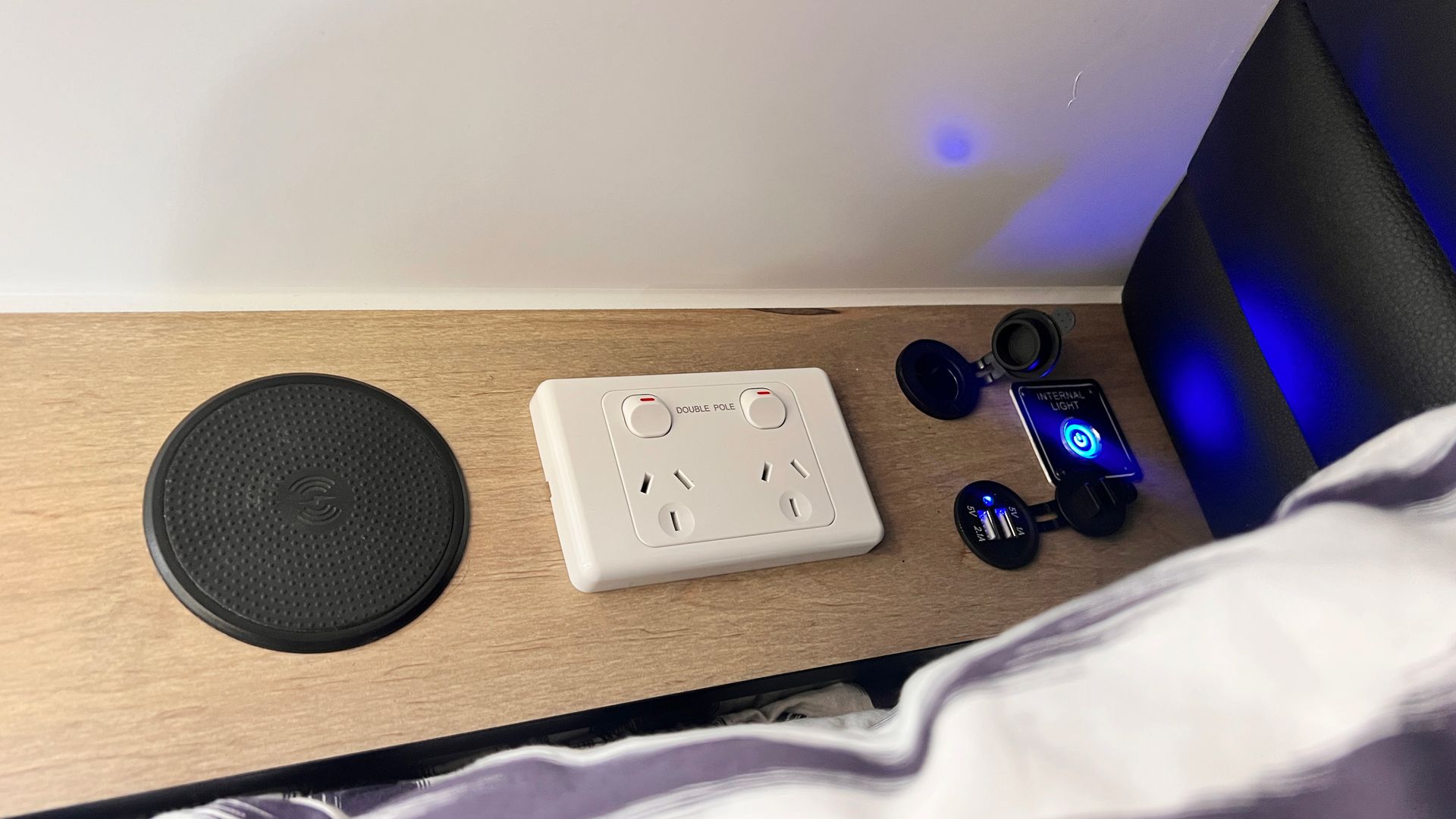 A bedside table with a speaker , a charger , and a socket.