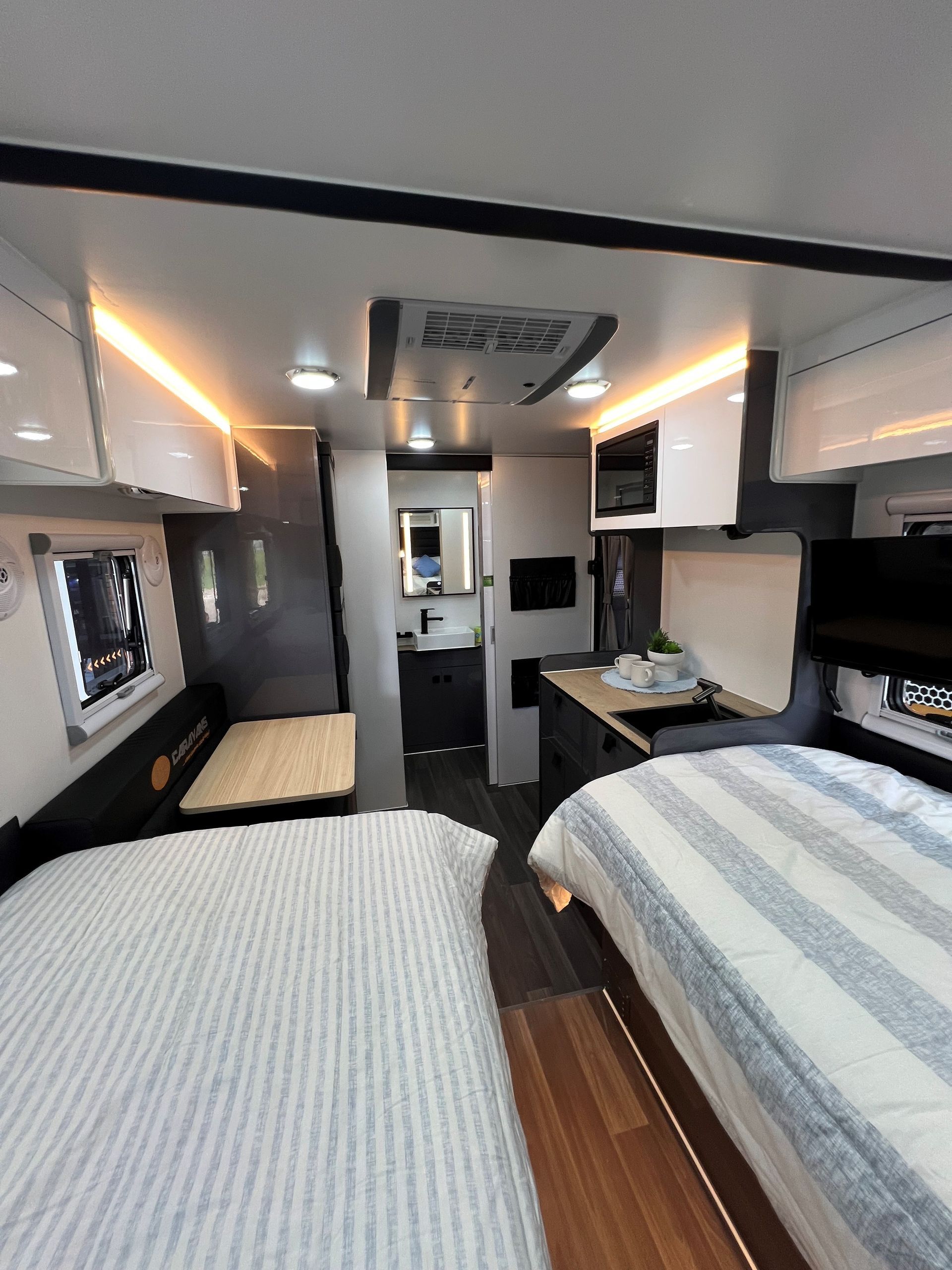 The inside of a rv with a bed and a table.