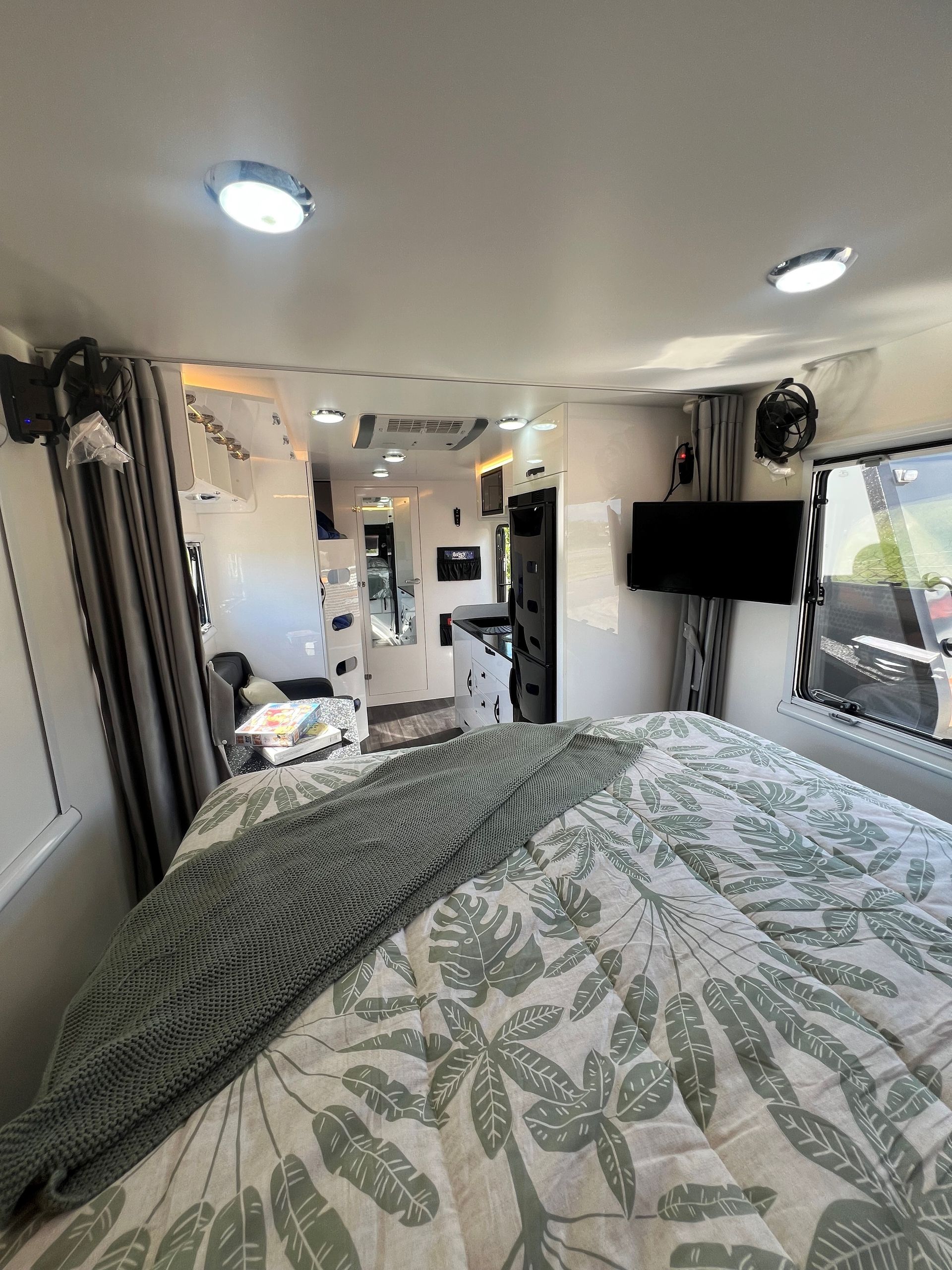 A bedroom in a camper van with a bed and a television.