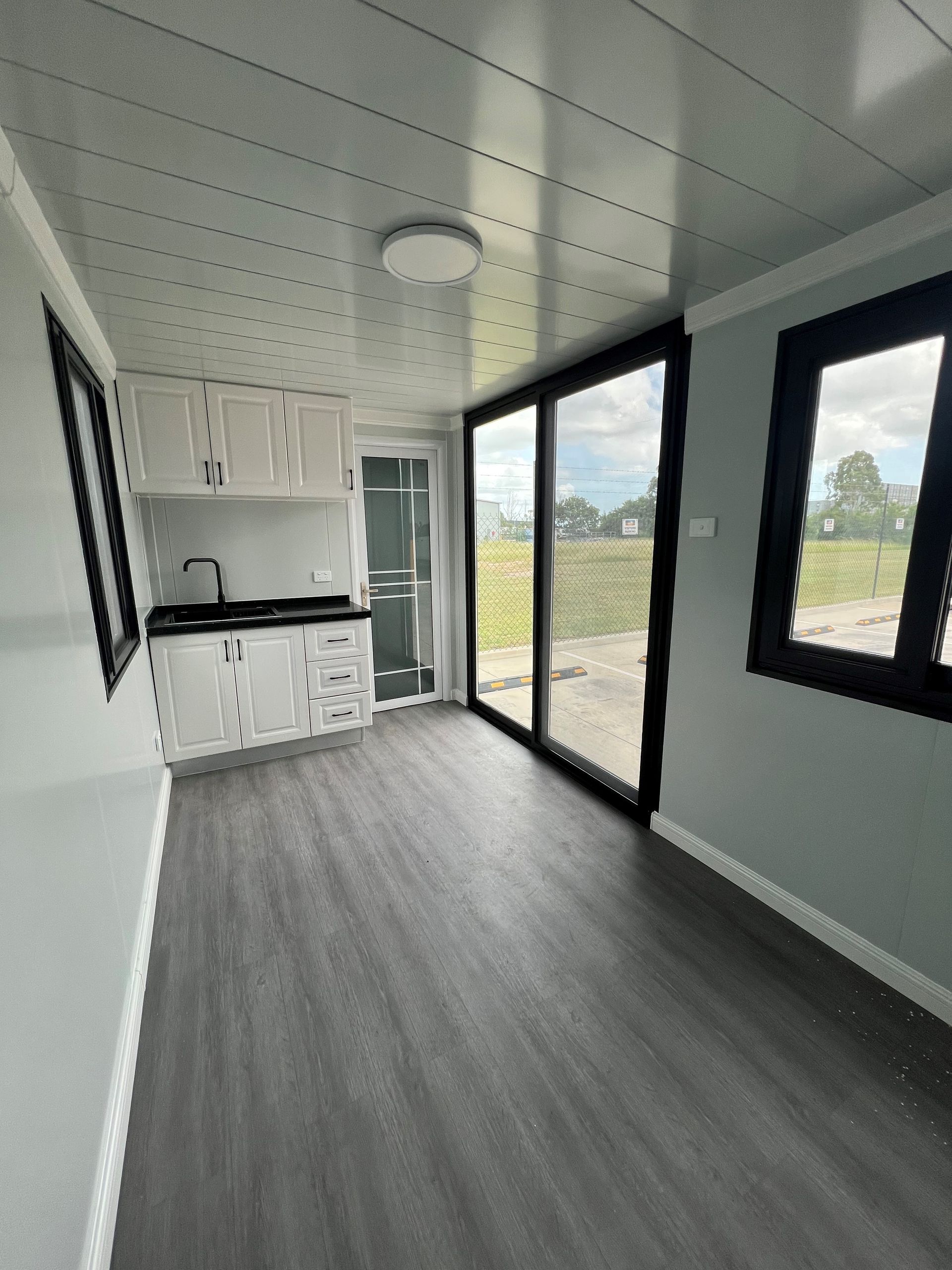 An empty room with a kitchen and sliding glass doors