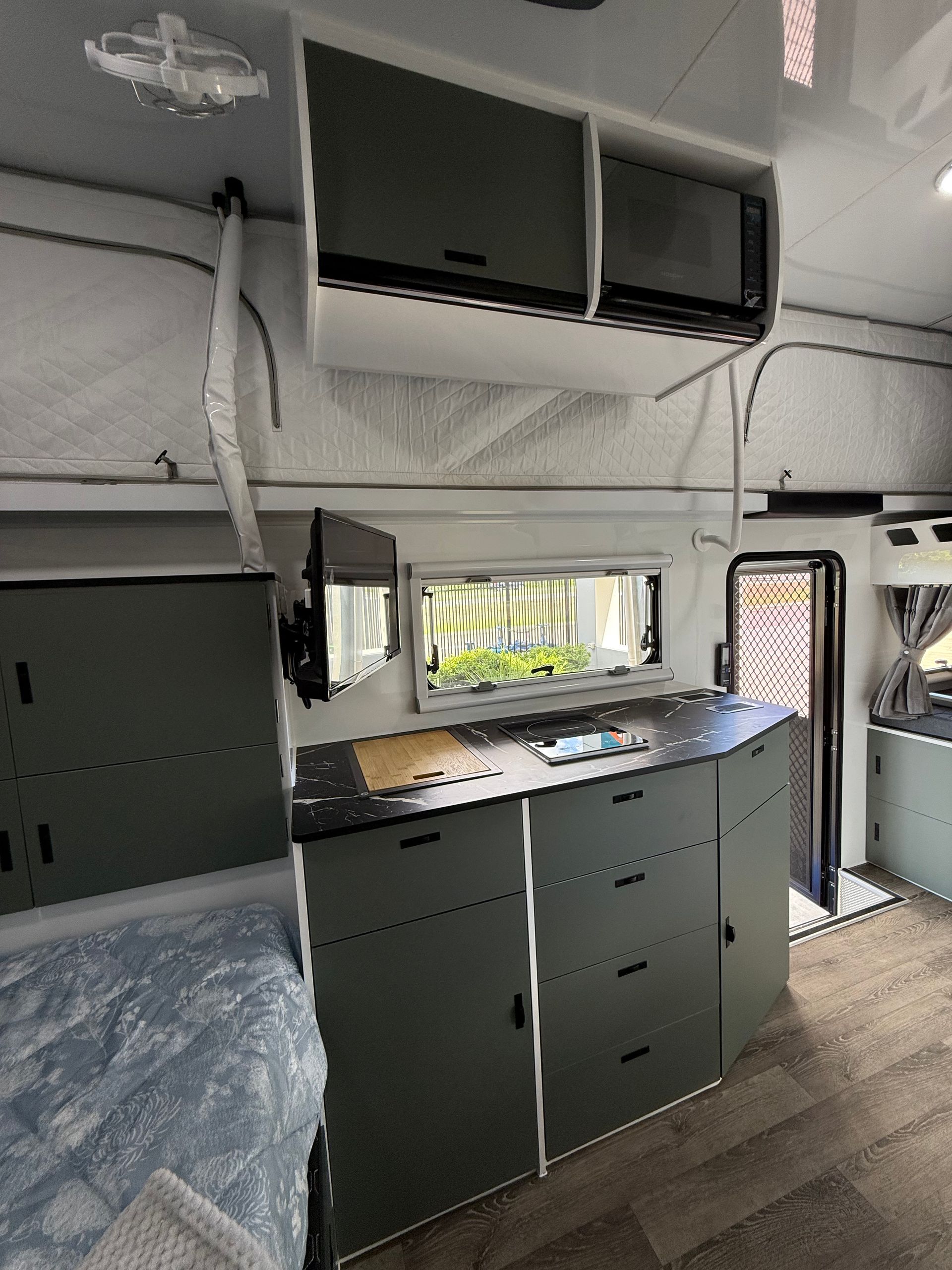 A kitchen in a camper with a bed and a window