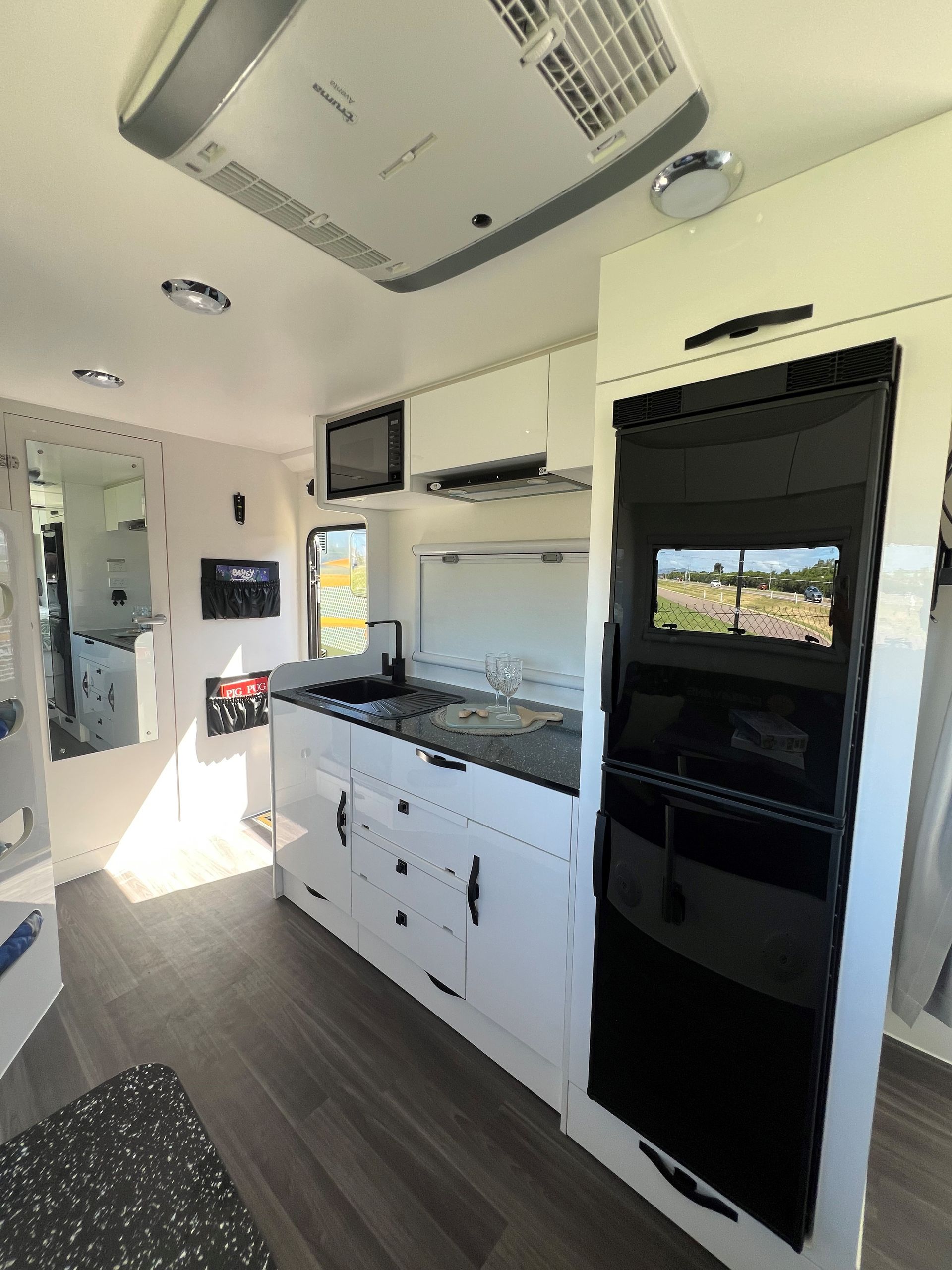 A kitchen with white cabinets , a black refrigerator and a television.