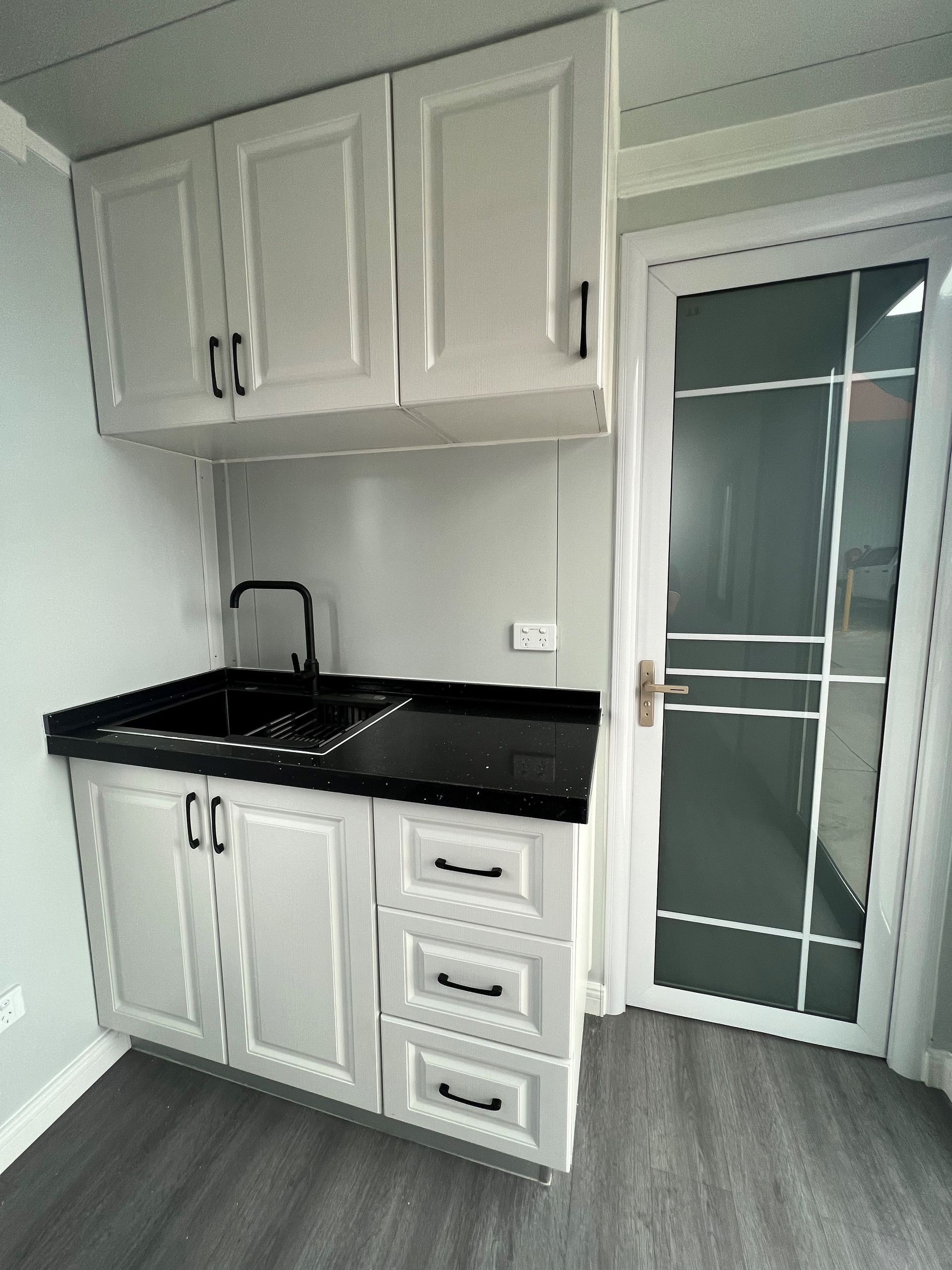 A kitchen with white cabinets and a black counter top
