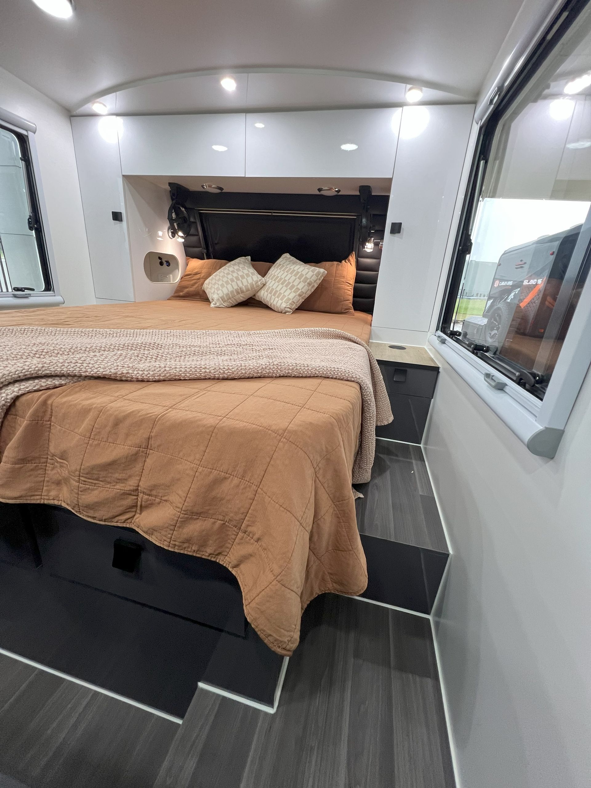 A bedroom in a camper with a bed and a window.