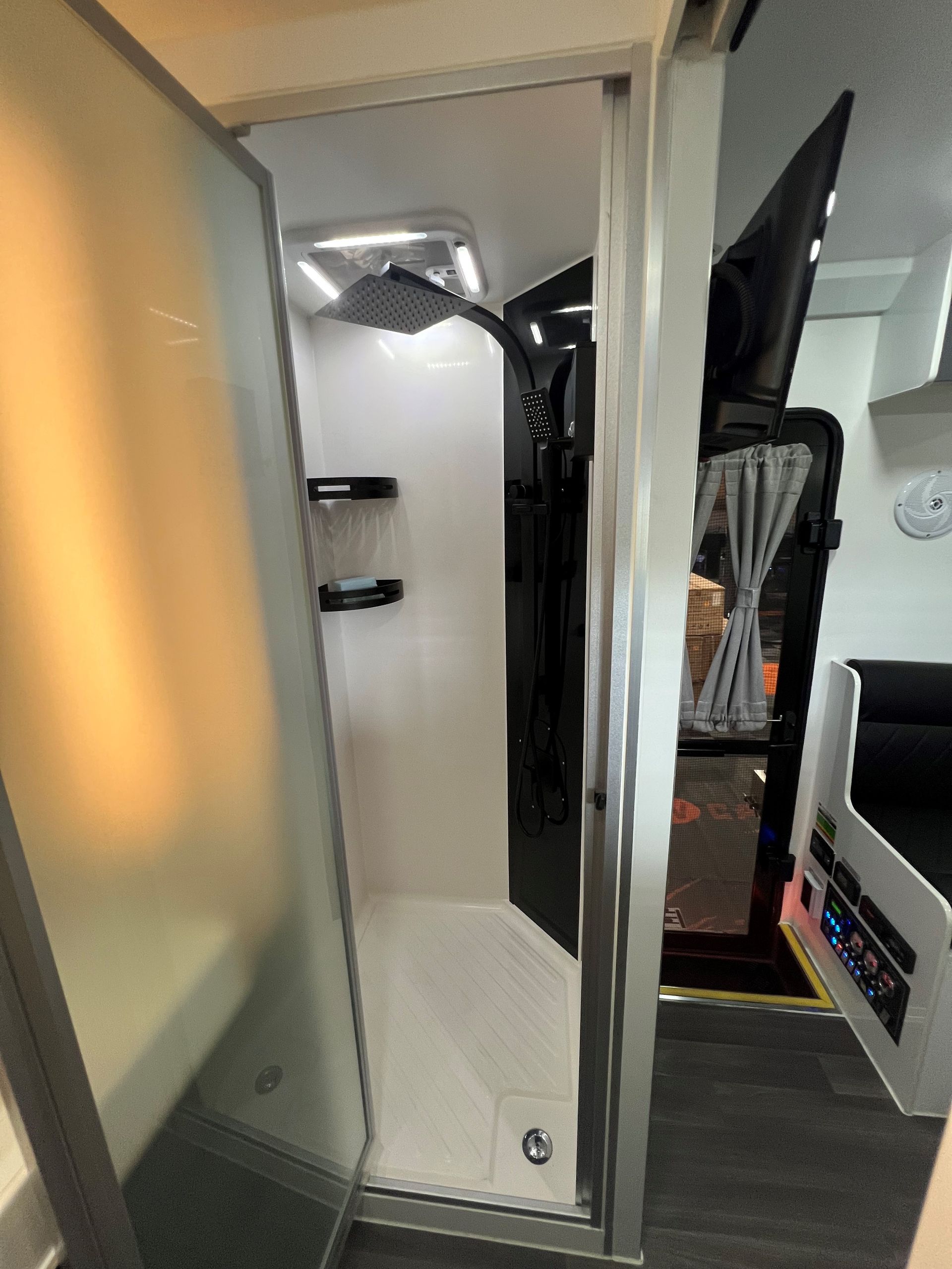 A bathroom in a camper with a shower and a television.