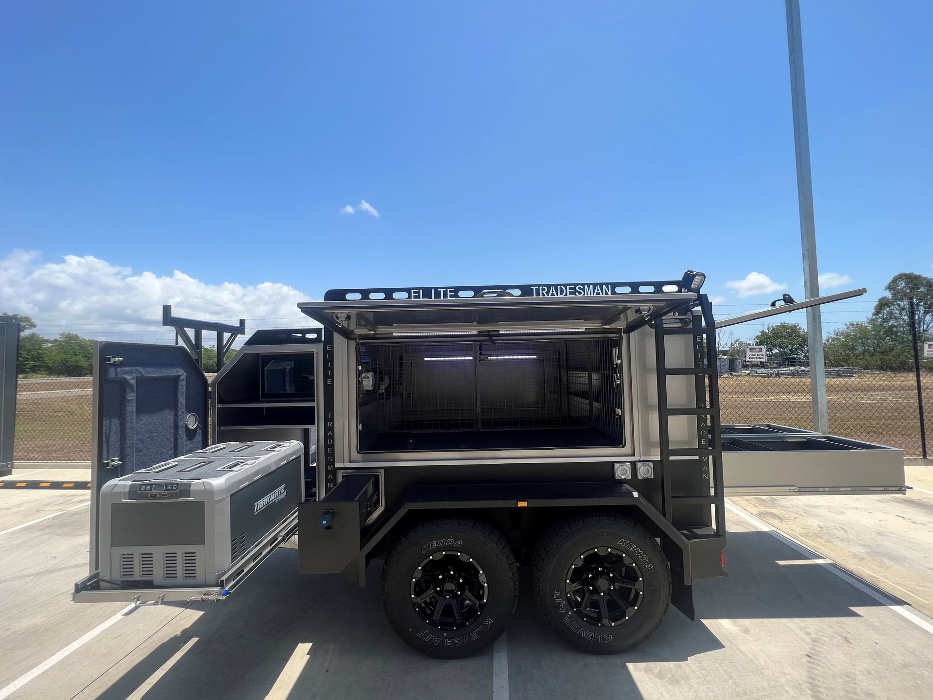 A trailer with the doors open is parked in a parking lot.