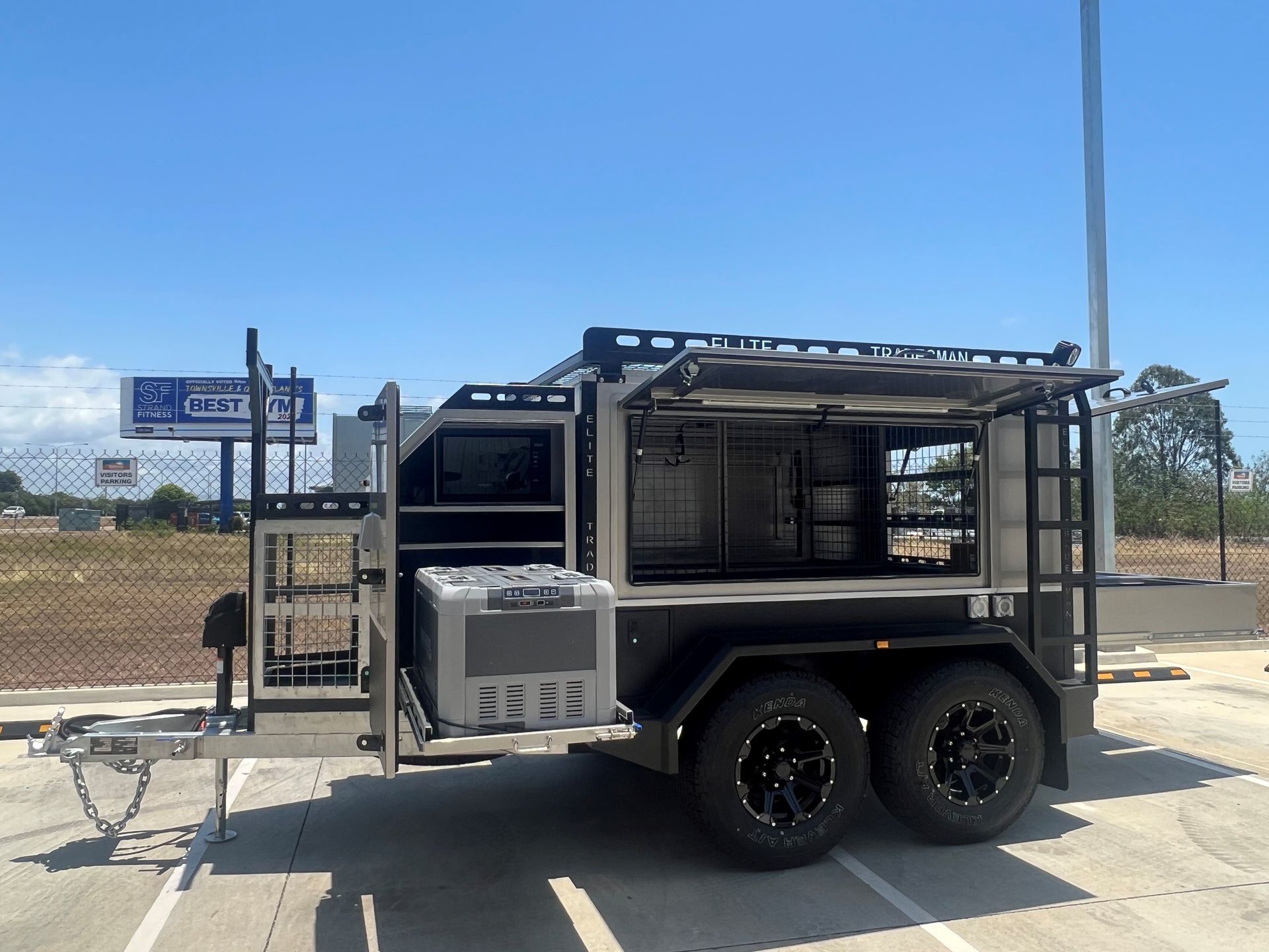 A trailer is parked in a parking lot with a billboard in the background.
