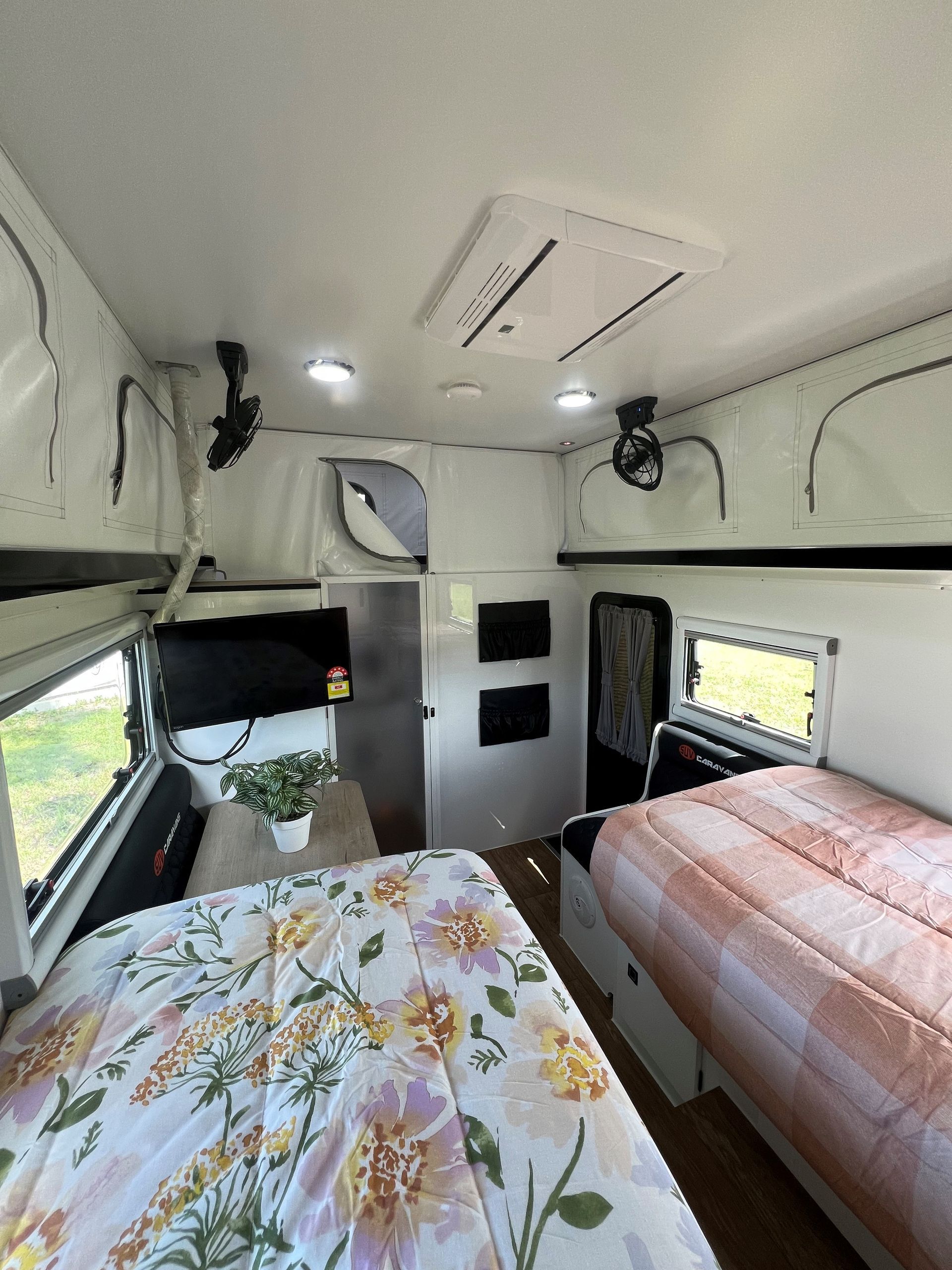 A bedroom in a camper with two beds and a ceiling fan.