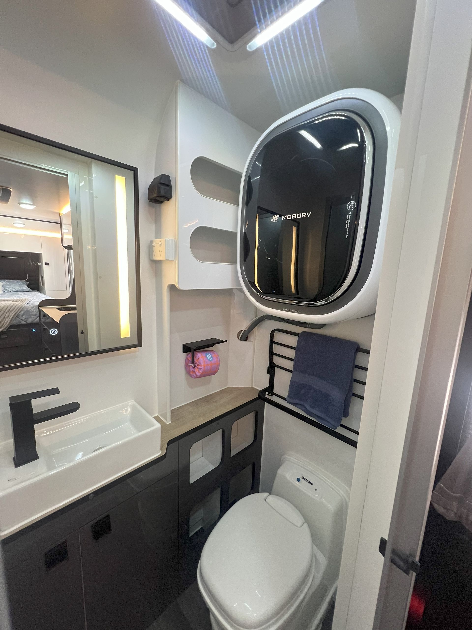A bathroom with a toilet , sink and mirror.