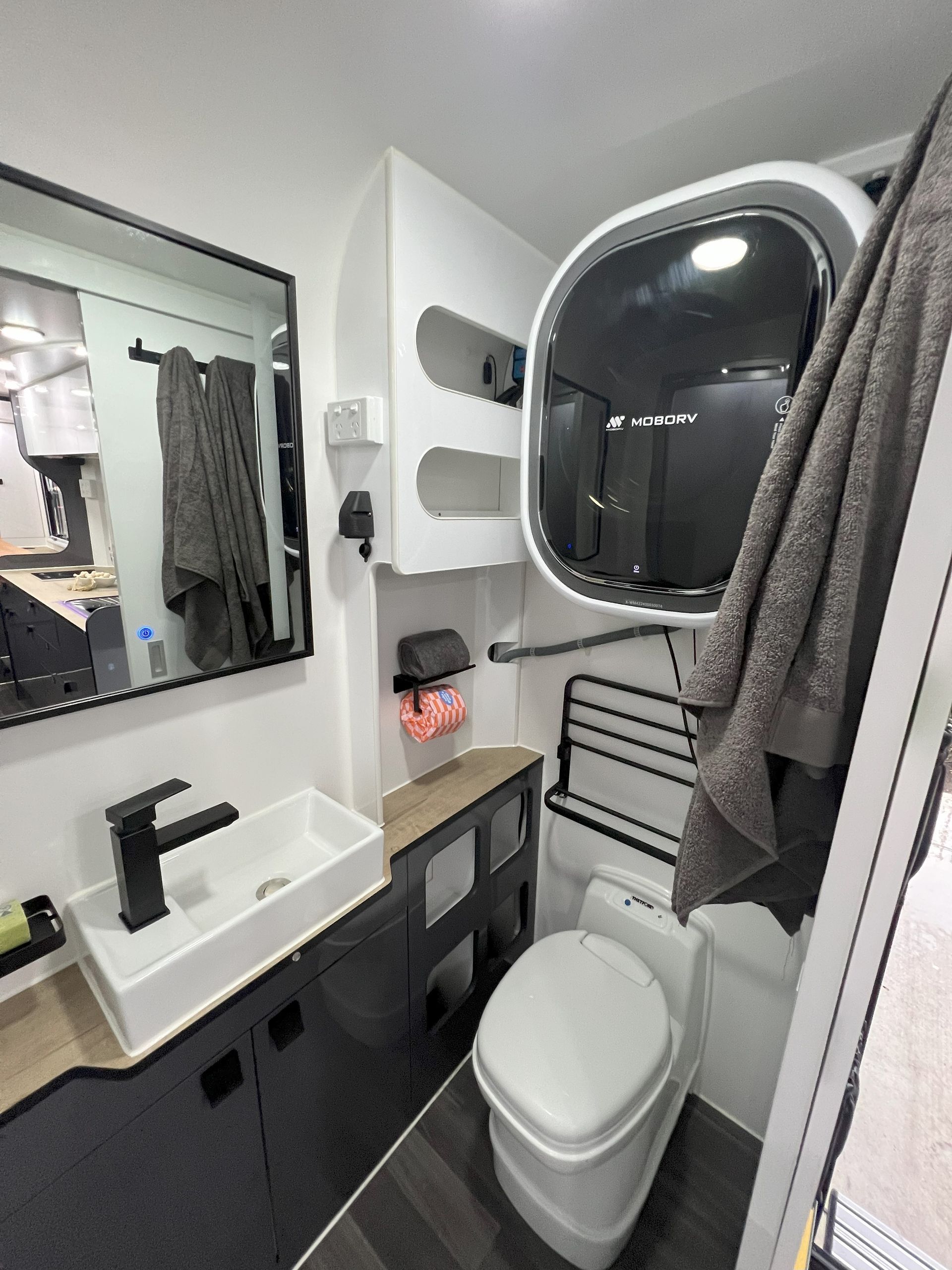 A bathroom with a toilet , sink and mirror.