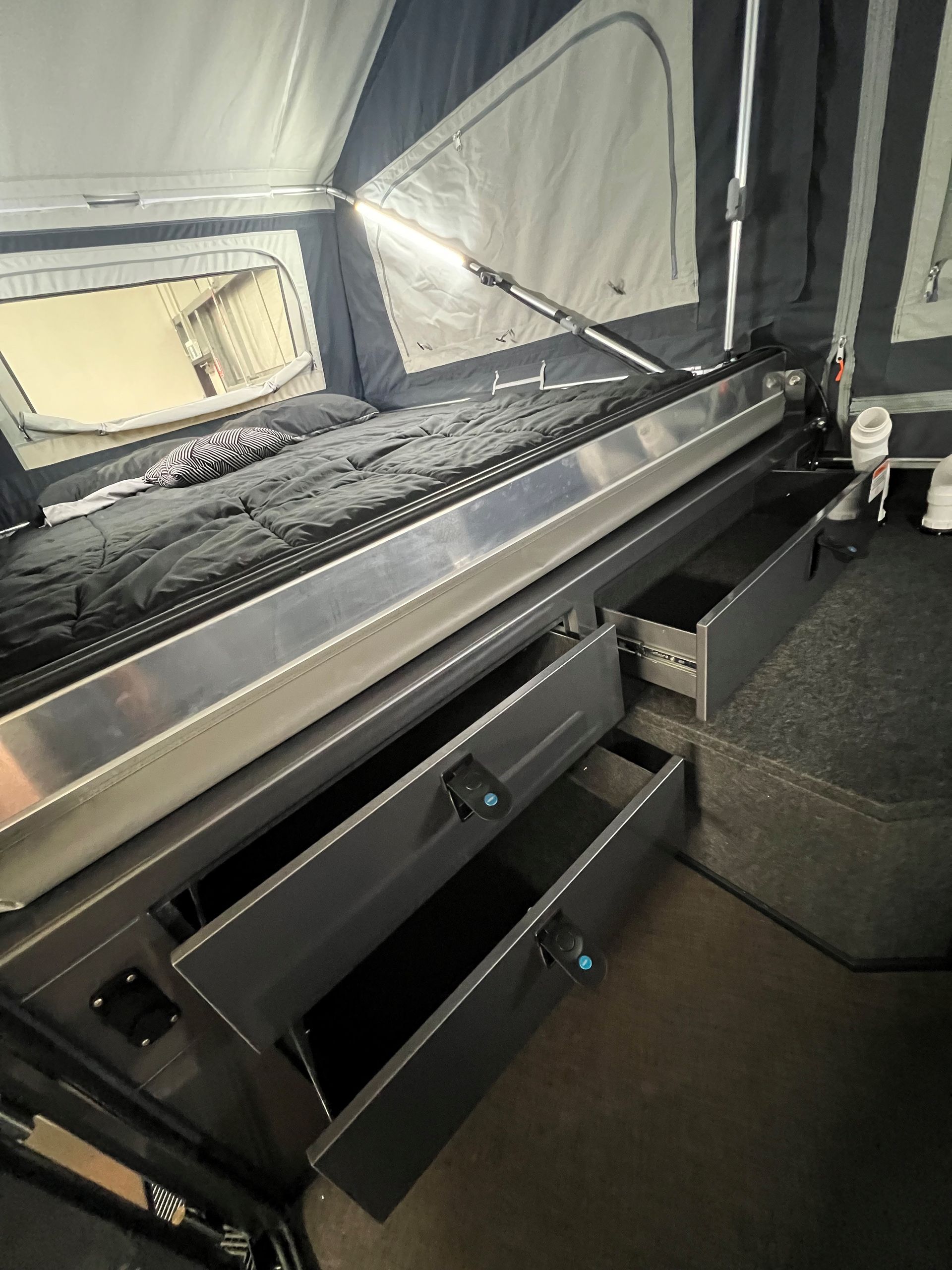 A camper with a bed and drawers underneath it.