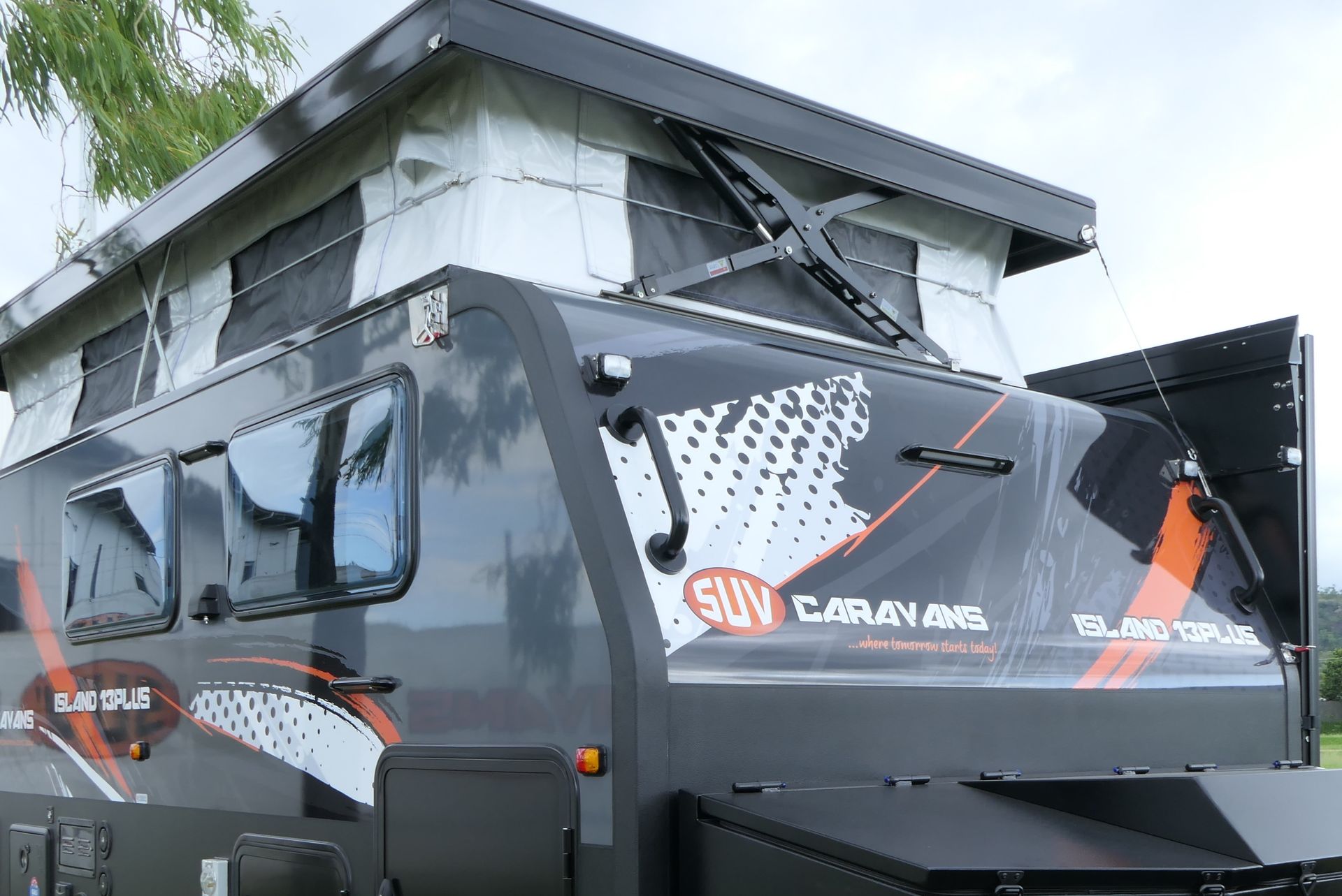 A camper with a tent on top of it is sitting in a warehouse.