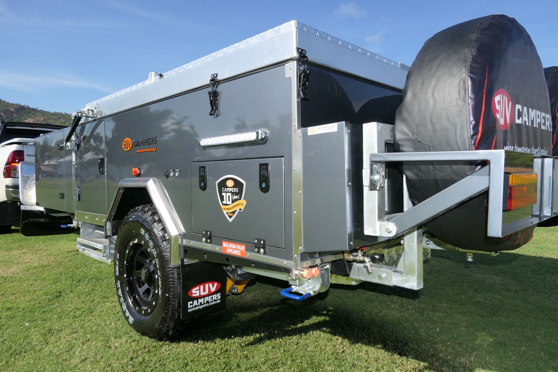 A camper trailer is parked in a grassy field next to a truck.
