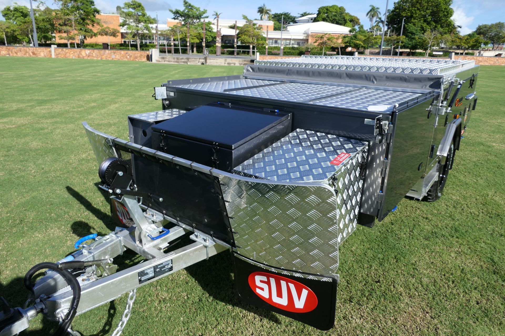 A suv trailer is parked on a lush green field.