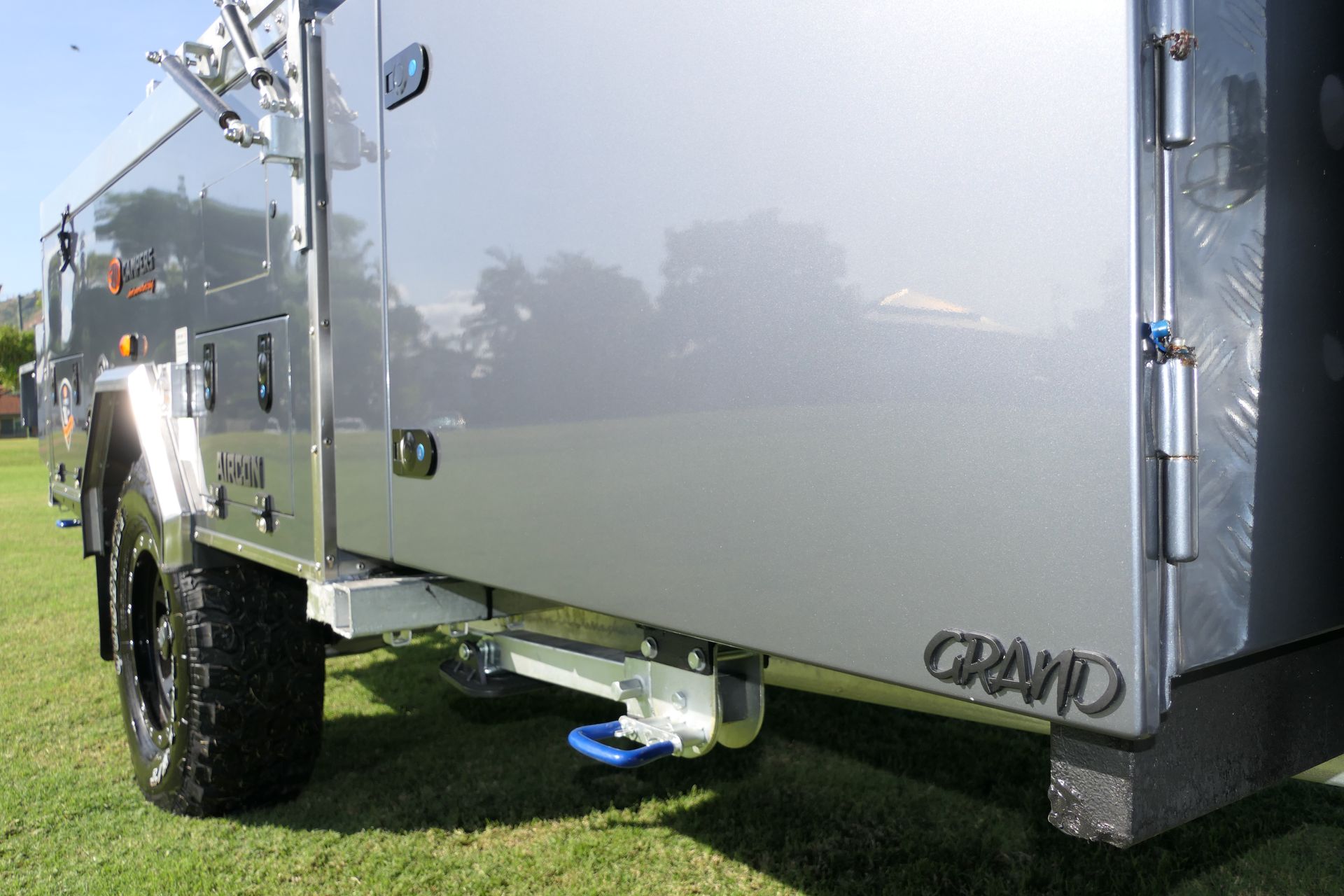 A silver grand trailer is parked in a grassy field