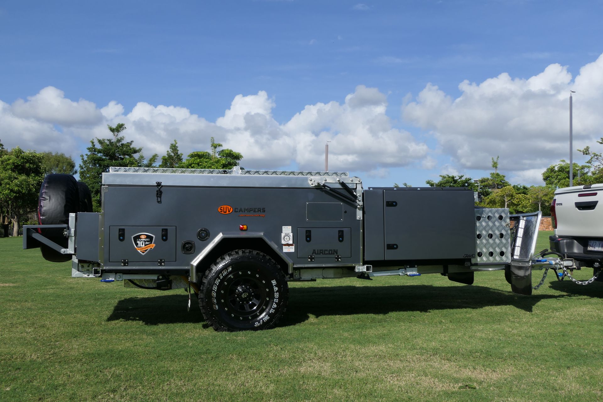 A trailer is parked next to a truck in a grassy field.