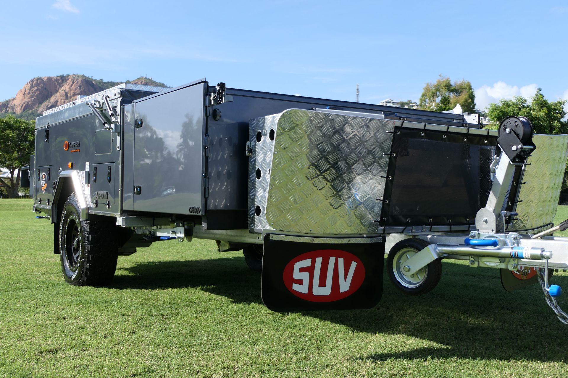 A suv with a trailer attached to it is parked in a grassy field.