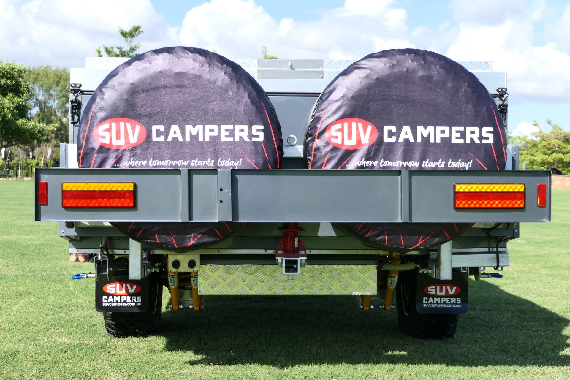 A suv campers trailer is parked in a grassy field