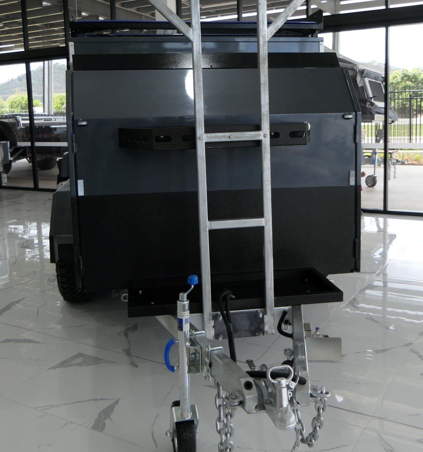 A black trailer with a ladder attached to it