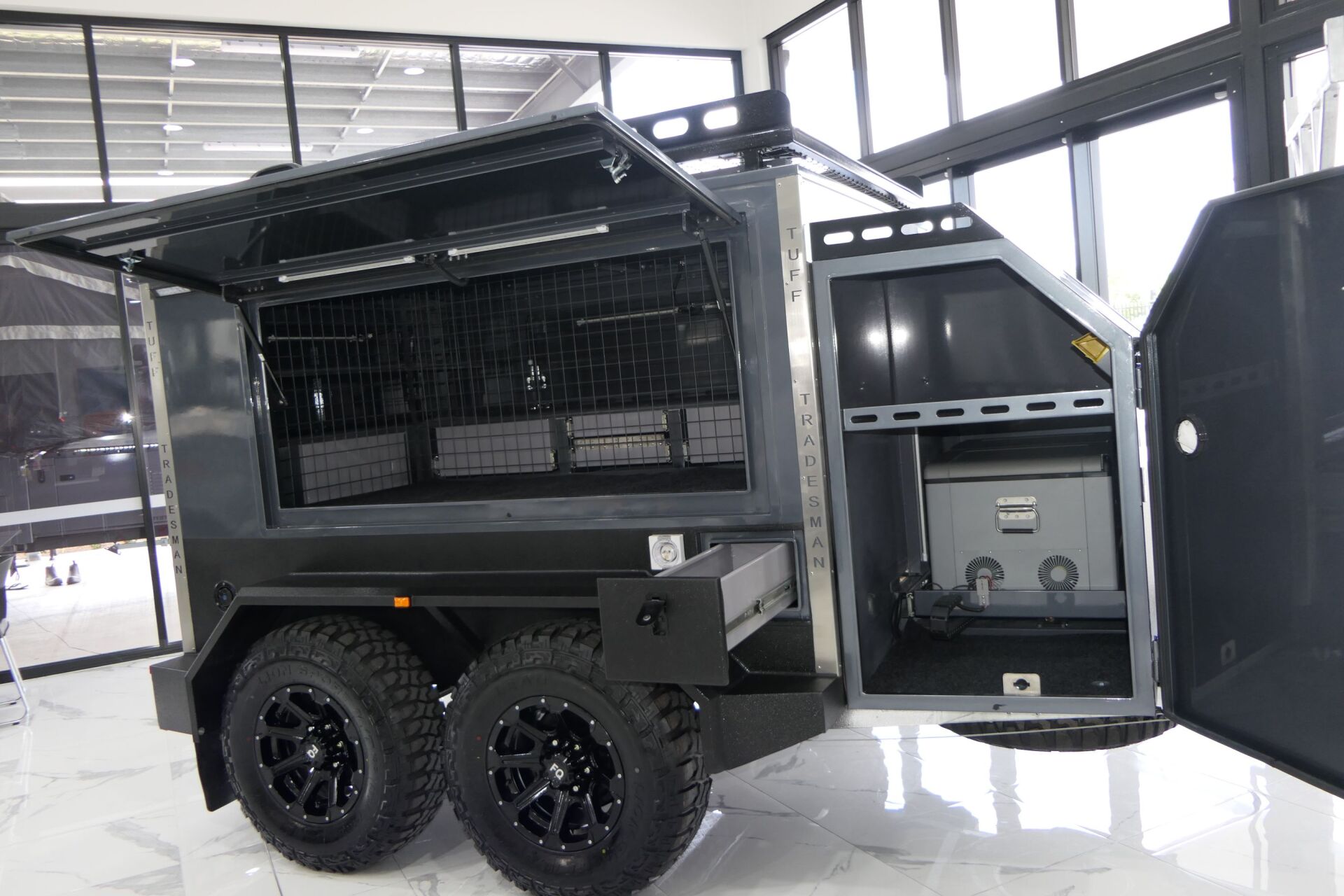 A black trailer with the doors open is parked in a room.