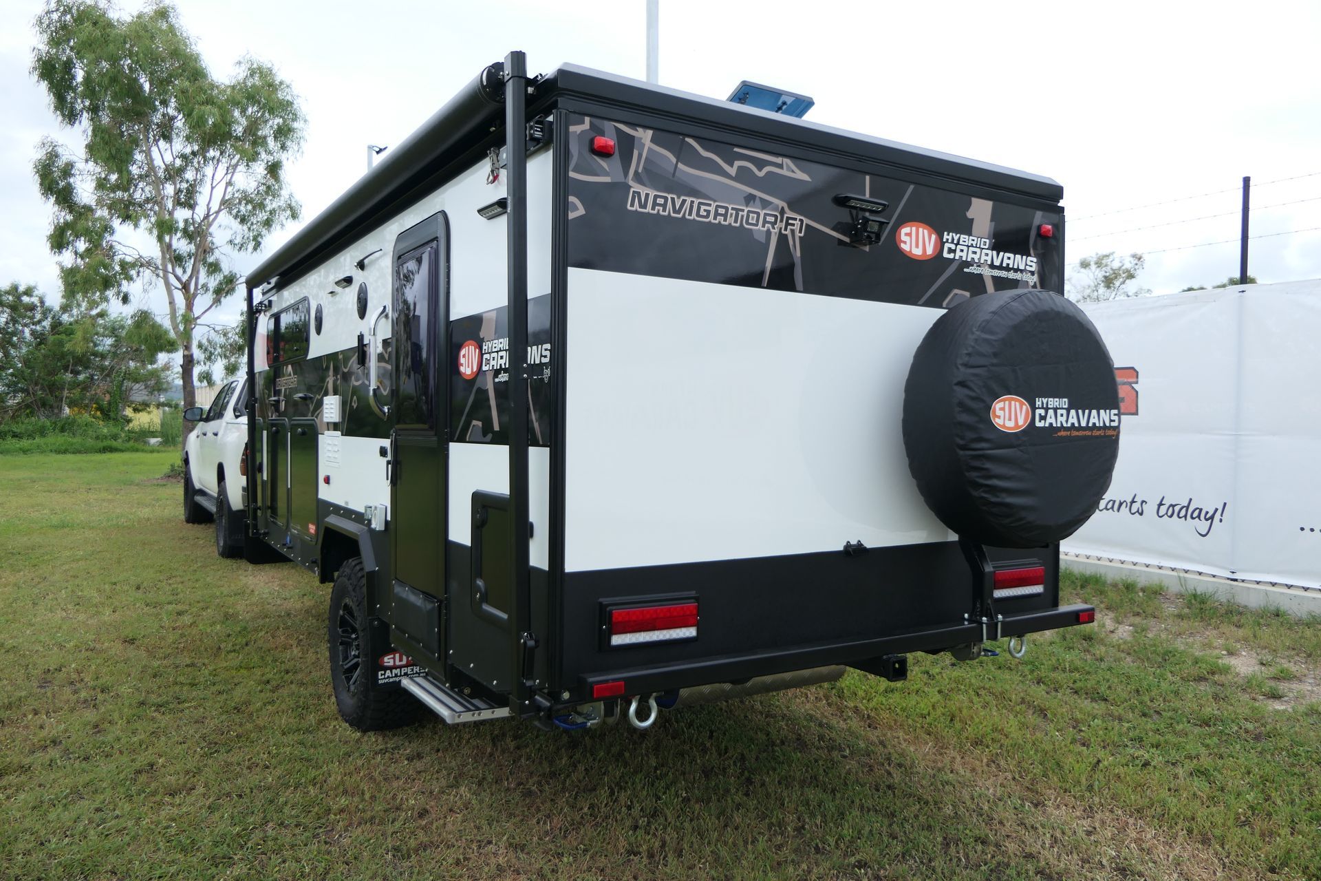 A black and white trailer is parked in a grassy field.