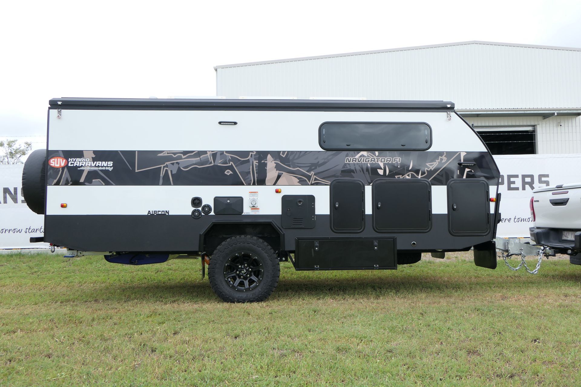A black and white camper trailer is parked in a grassy field.