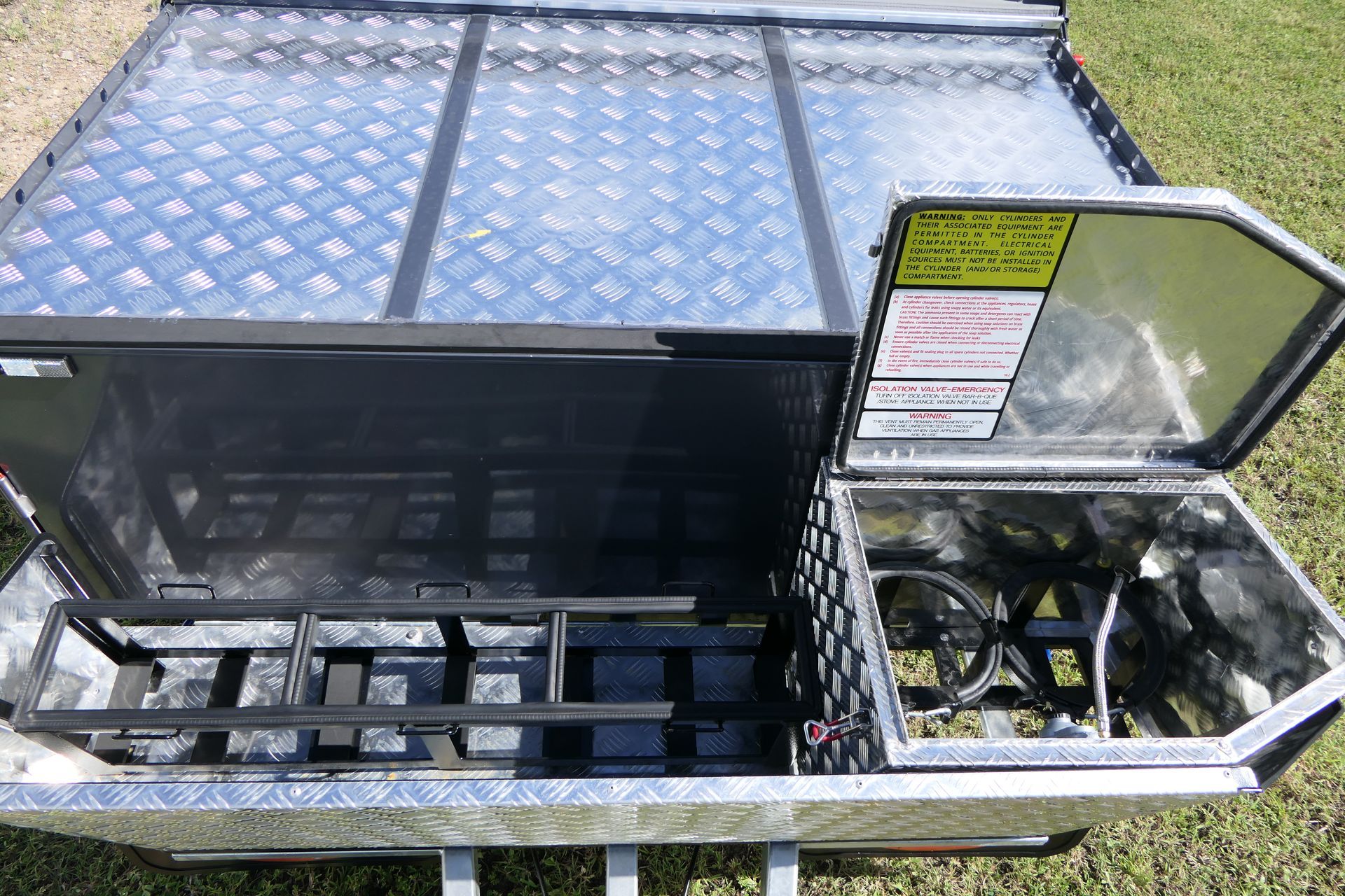 A trailer with the lid open is sitting on top of a lush green field.