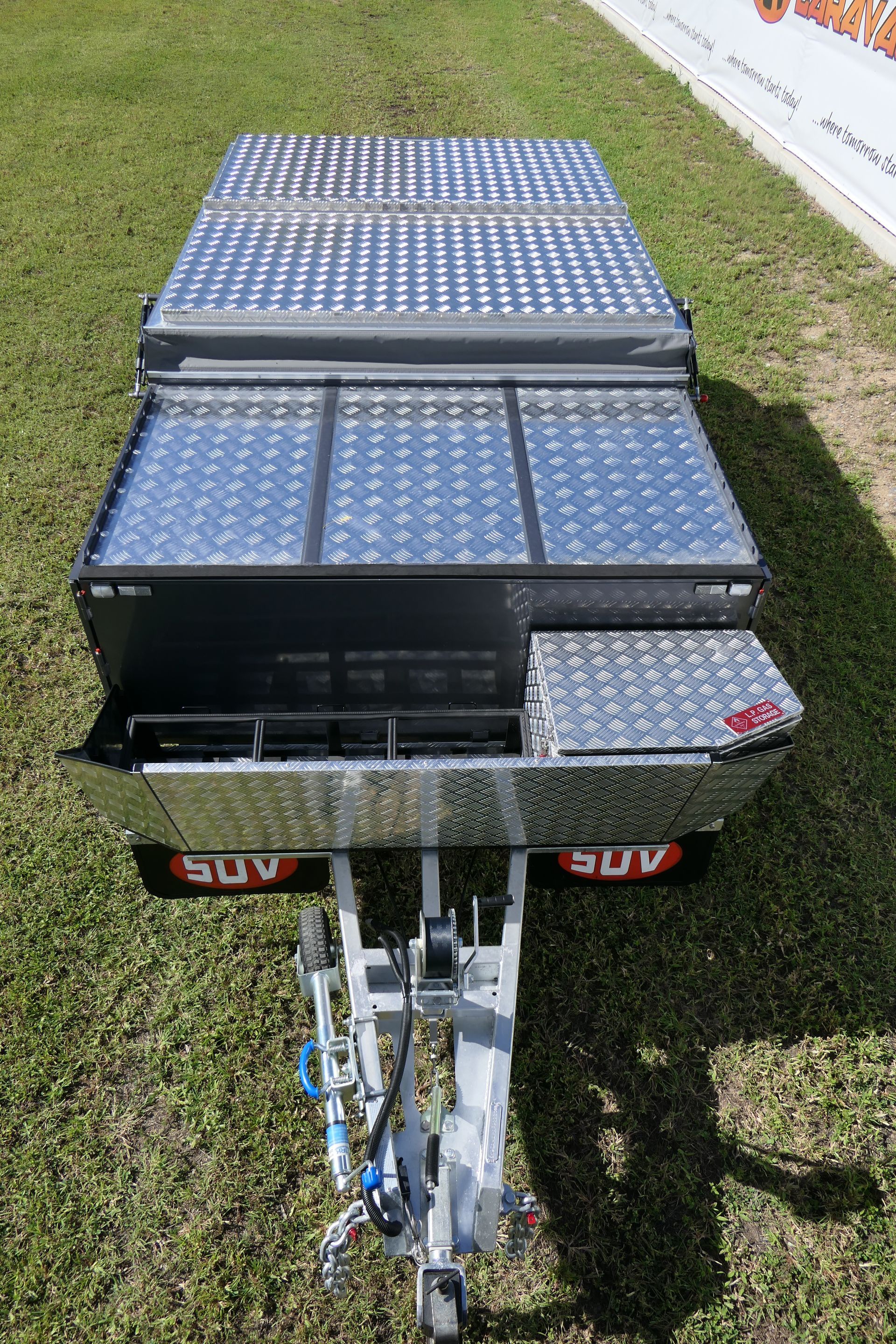 A trailer with a solar panel on top of it is parked in the grass.