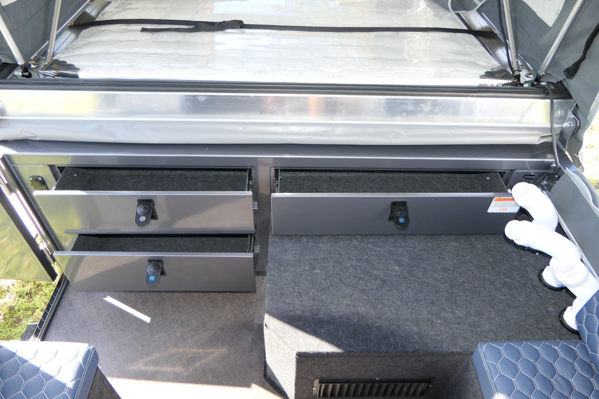 The inside of a truck with a bed and drawers underneath it.