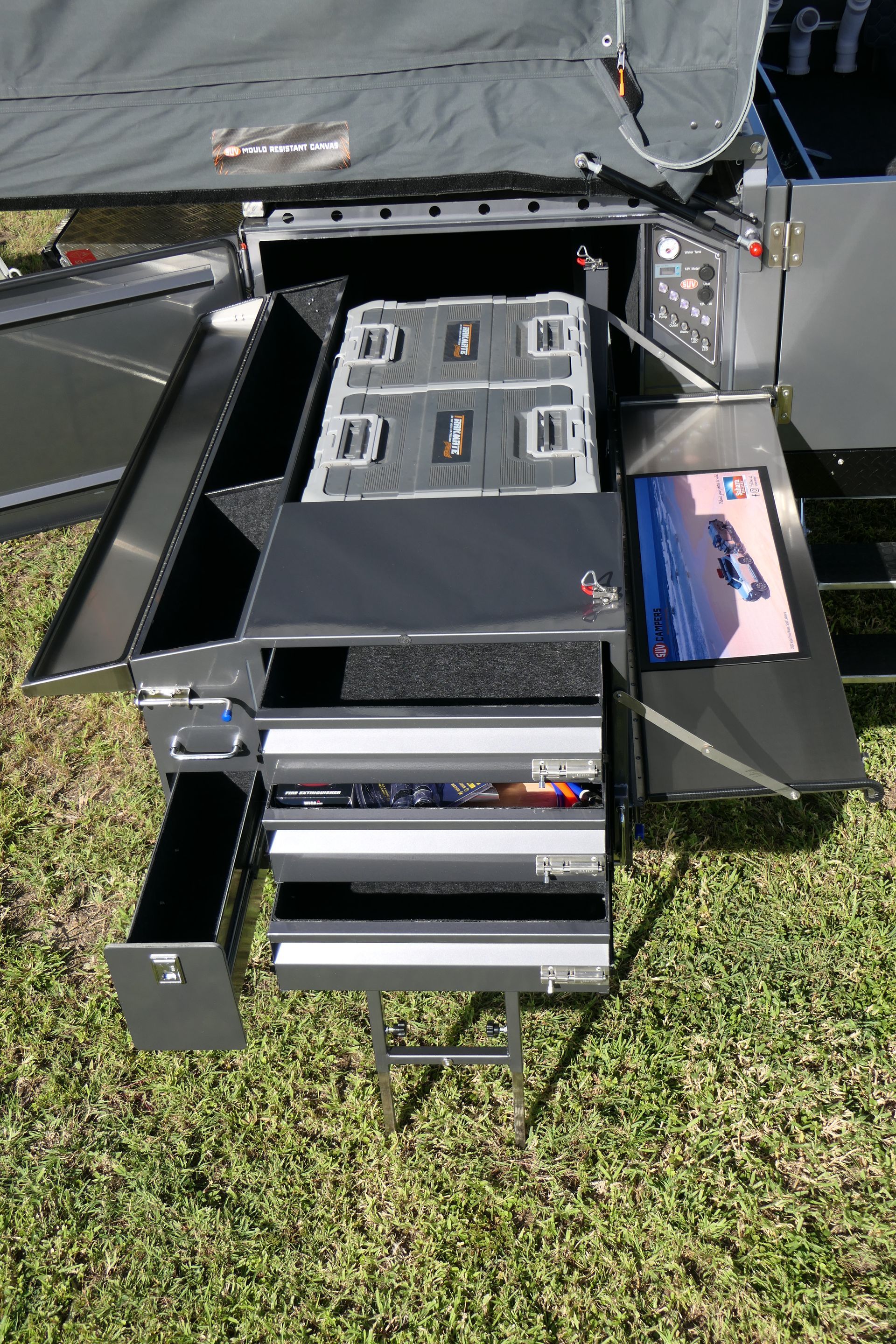 A stainless steel cabinet with drawers is sitting on top of a lush green field.