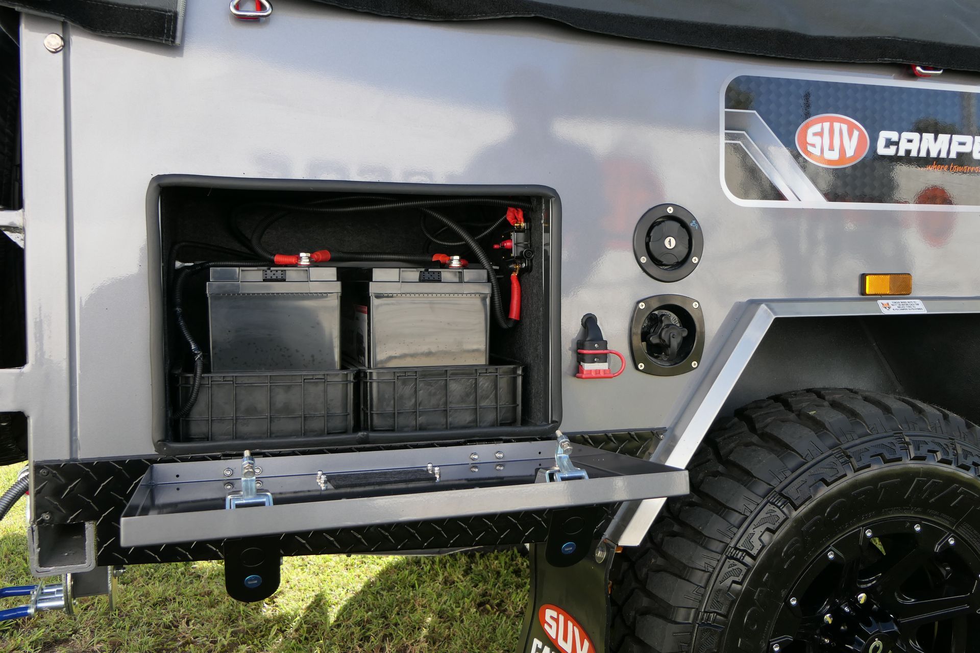The side of a suv camp trailer with two batteries in it.