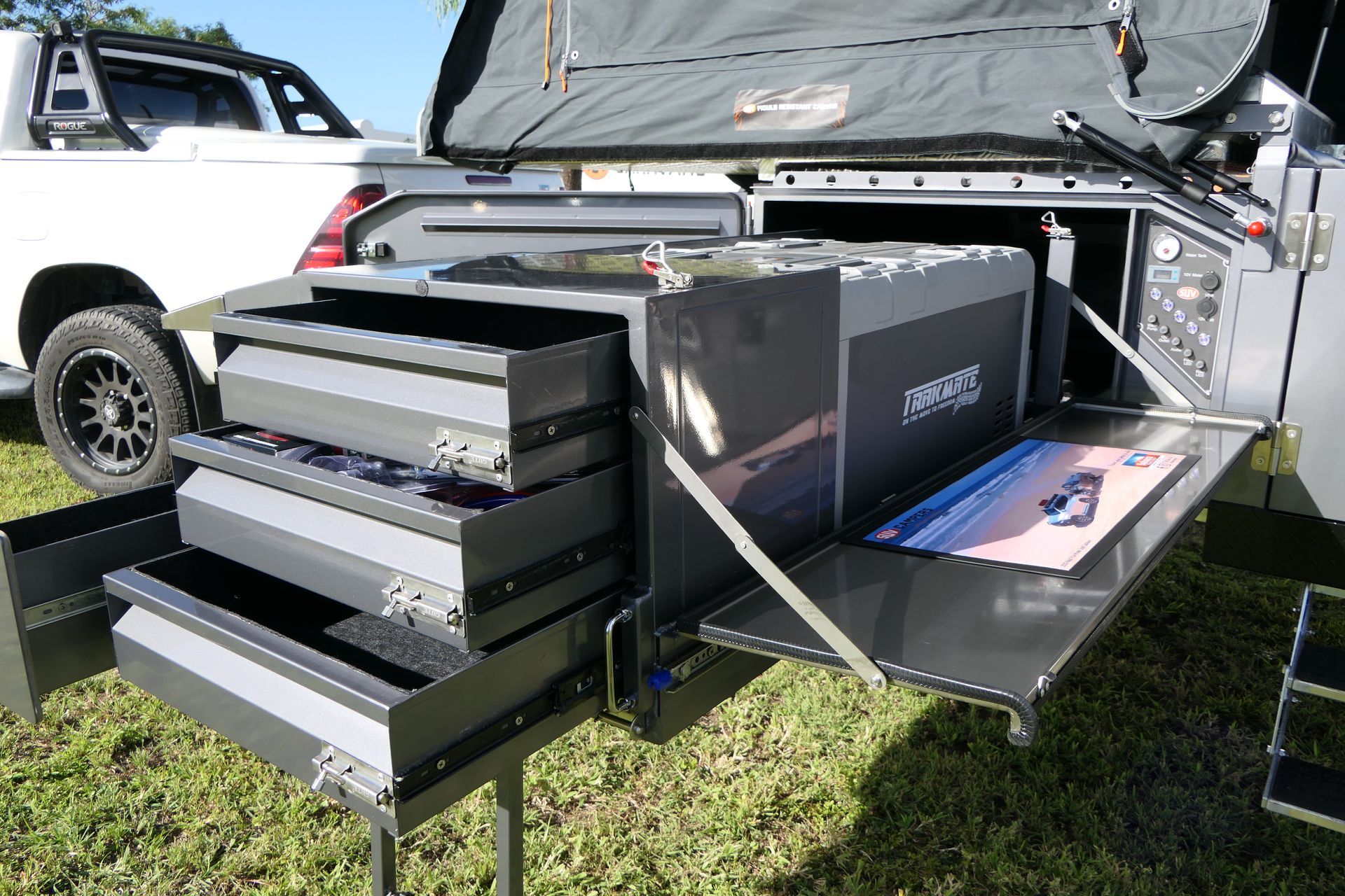 A white truck is parked next to a trailer with drawers open.