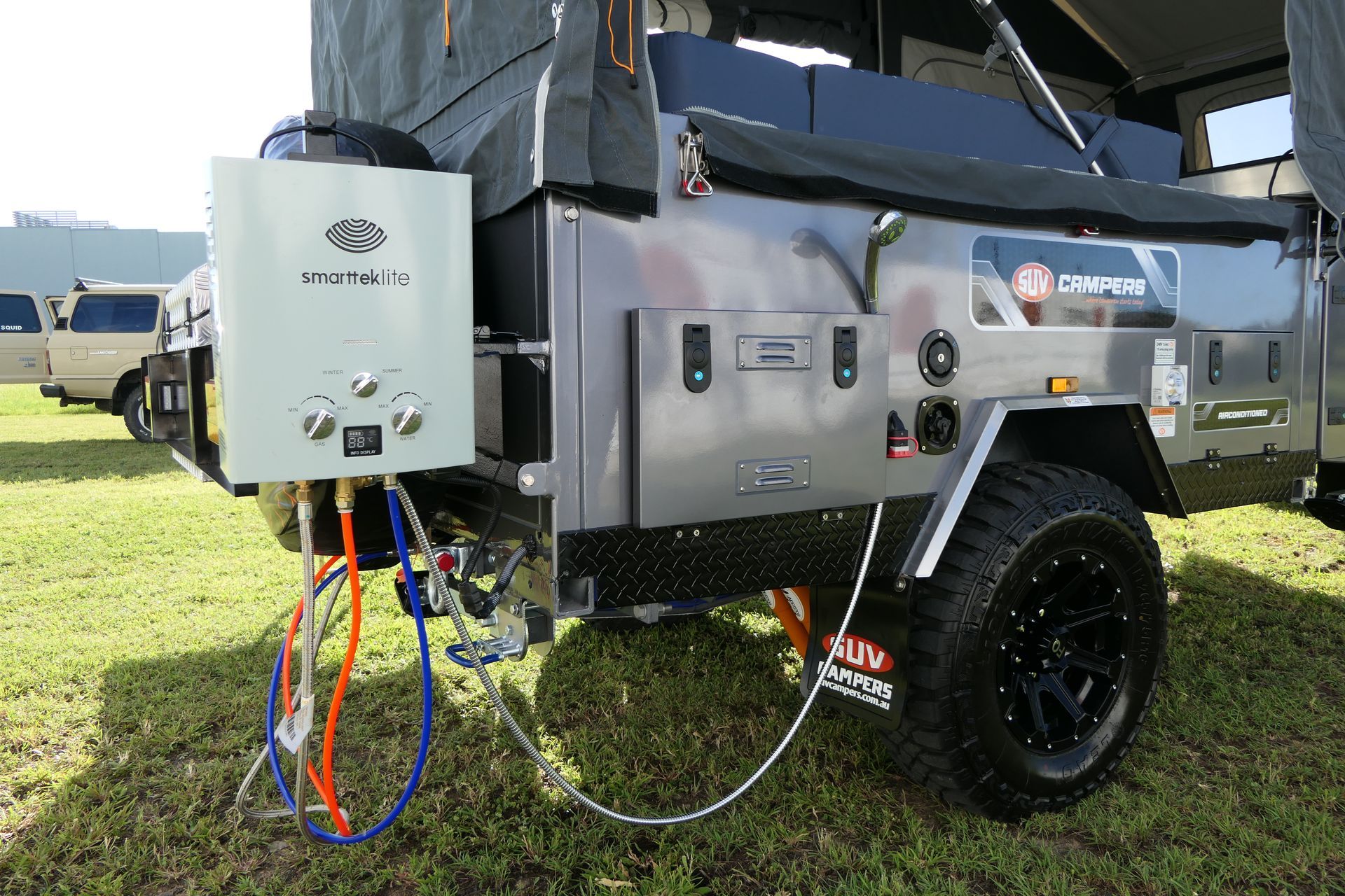 A trailer with a water heater attached to it is parked in a grassy field.