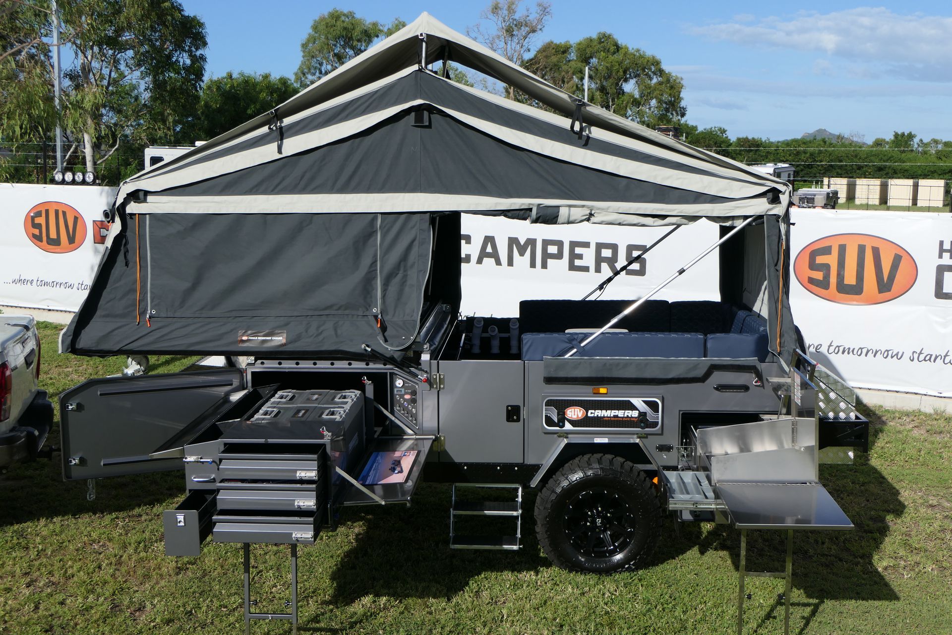 A trailer with a tent on top of it is parked in a field.