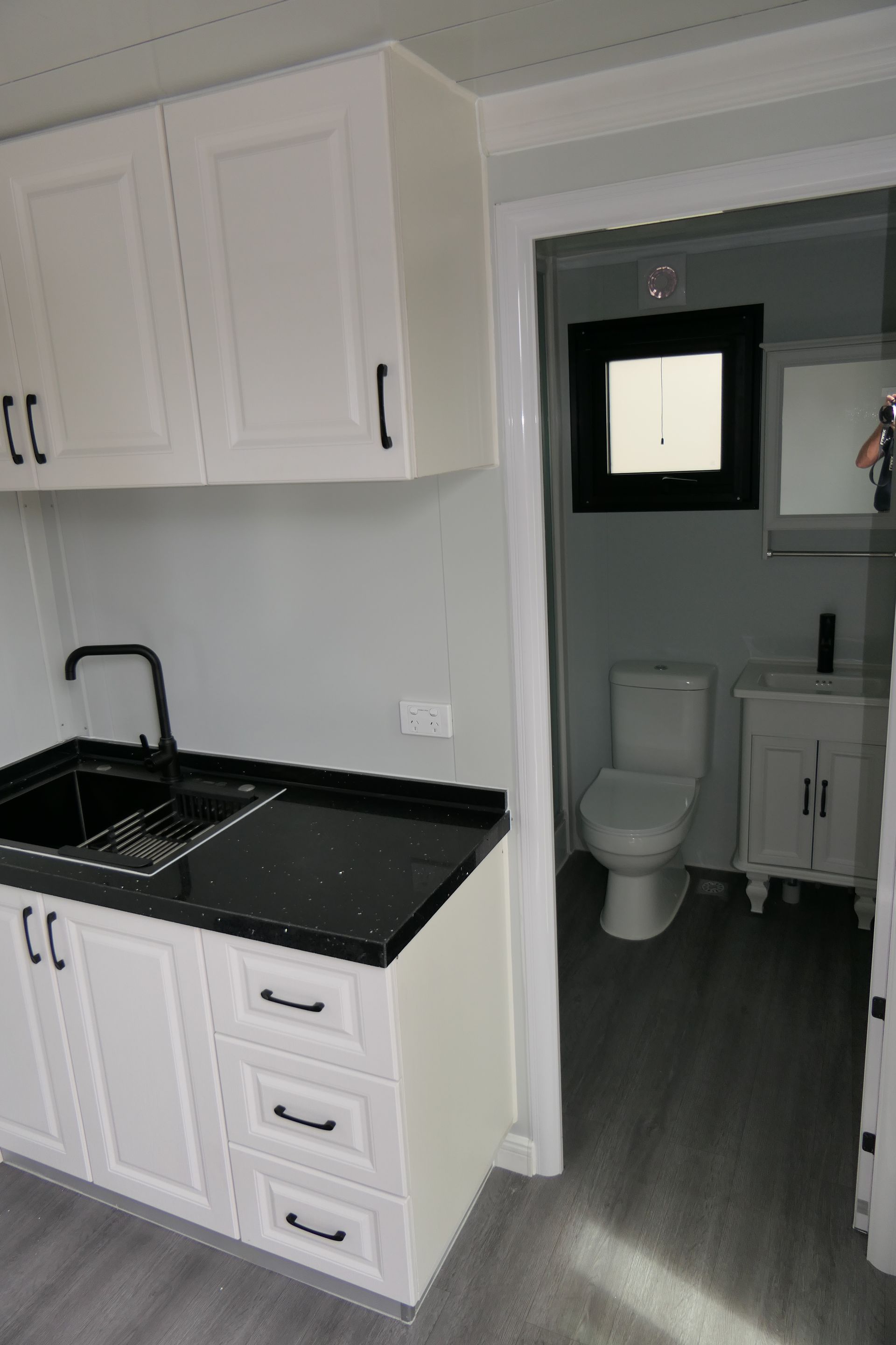 A kitchen with white cabinets , a sink , and a toilet.