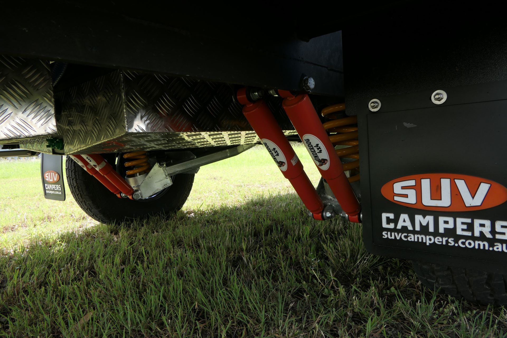 A suv is parked in the grass next to a sign that says suv campers