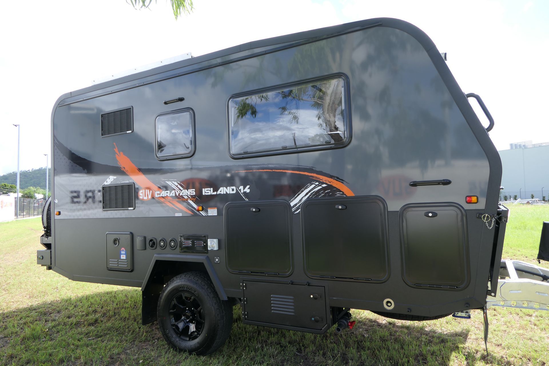 A black trailer is parked in a grassy field.