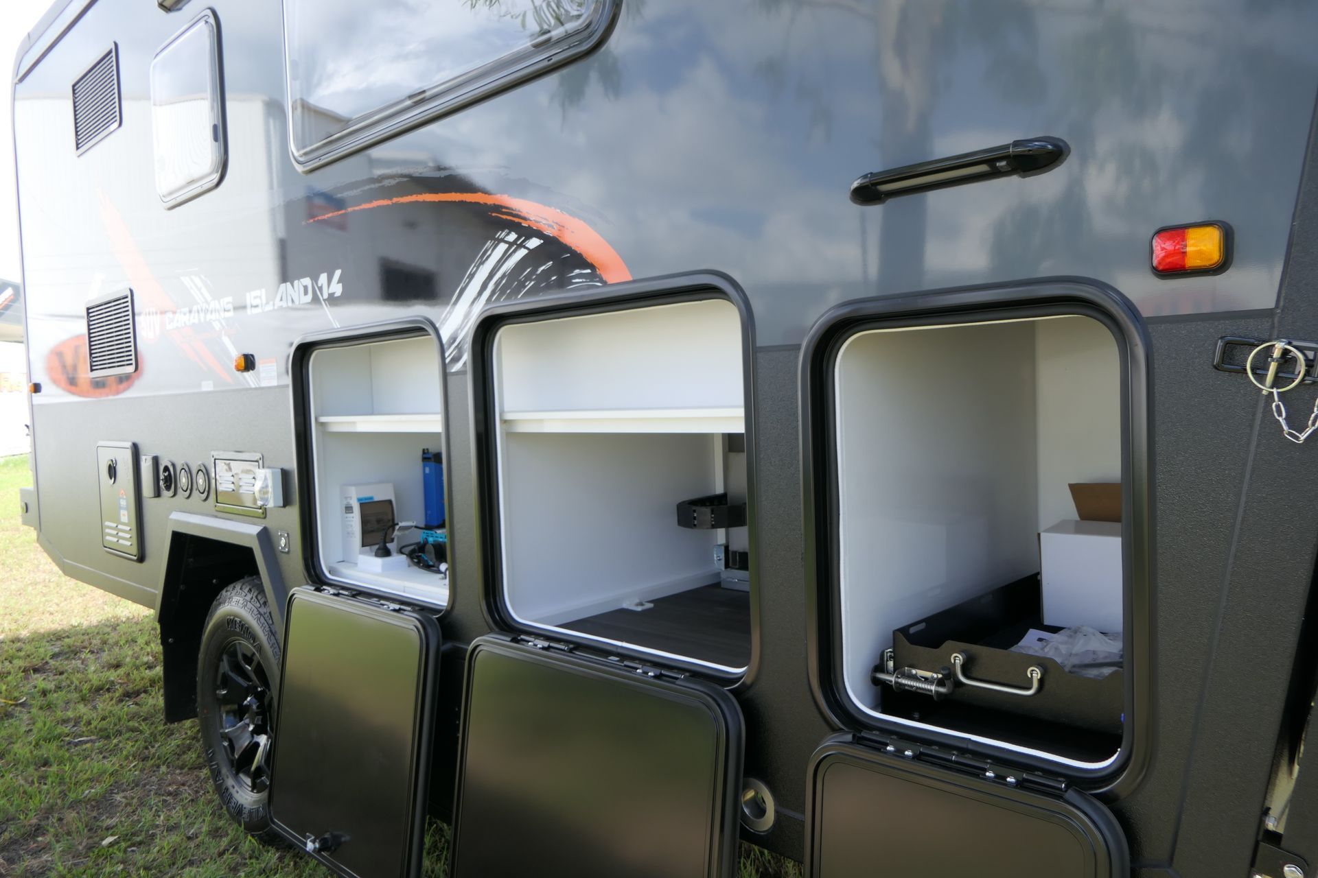 The back of a camper with its doors open and shelves.