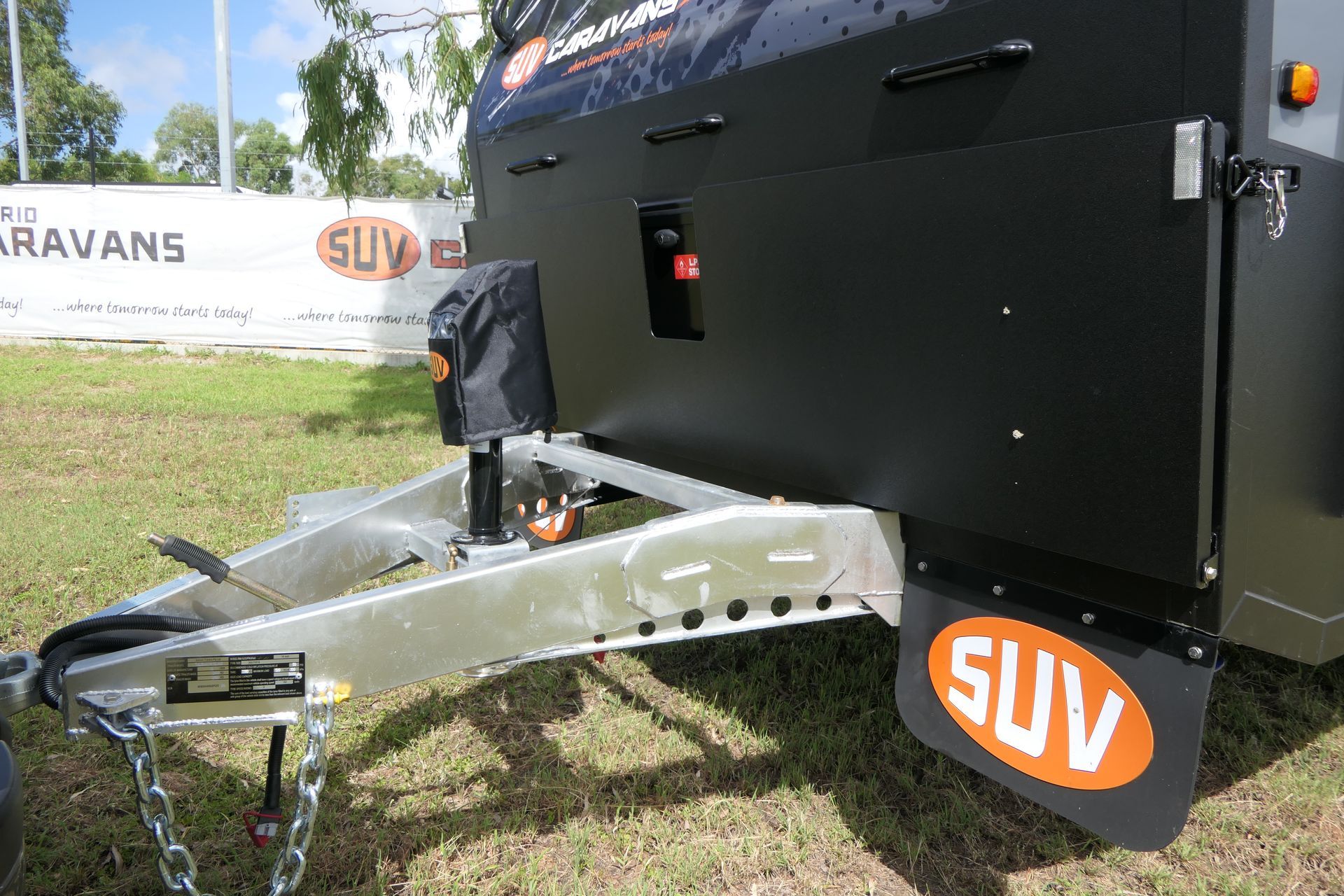 A black suv trailer is parked in a grassy field.