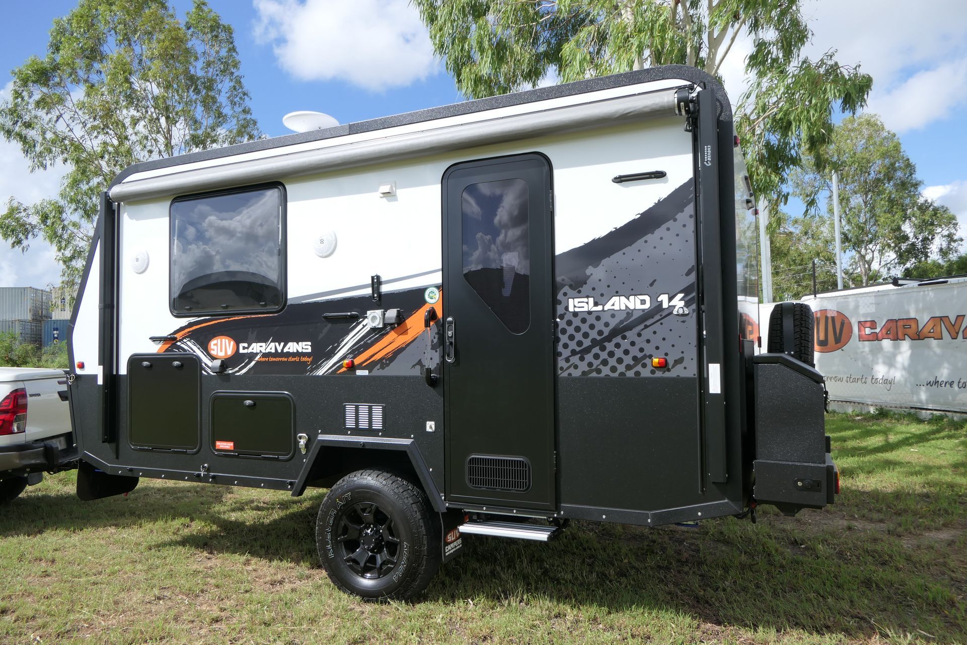 A black and white trailer is parked in a grassy field.