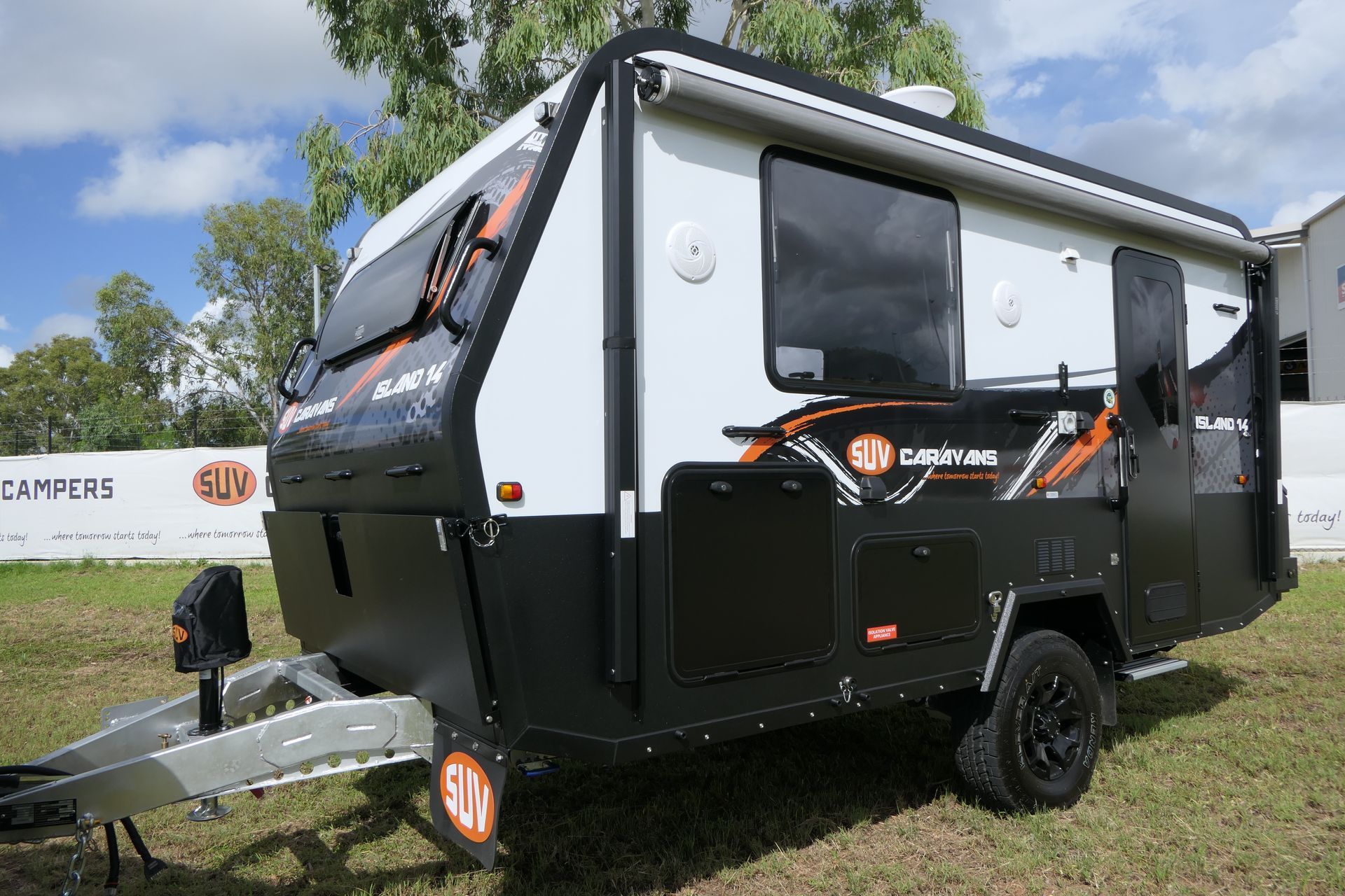 A black and white trailer is parked in a grassy field.