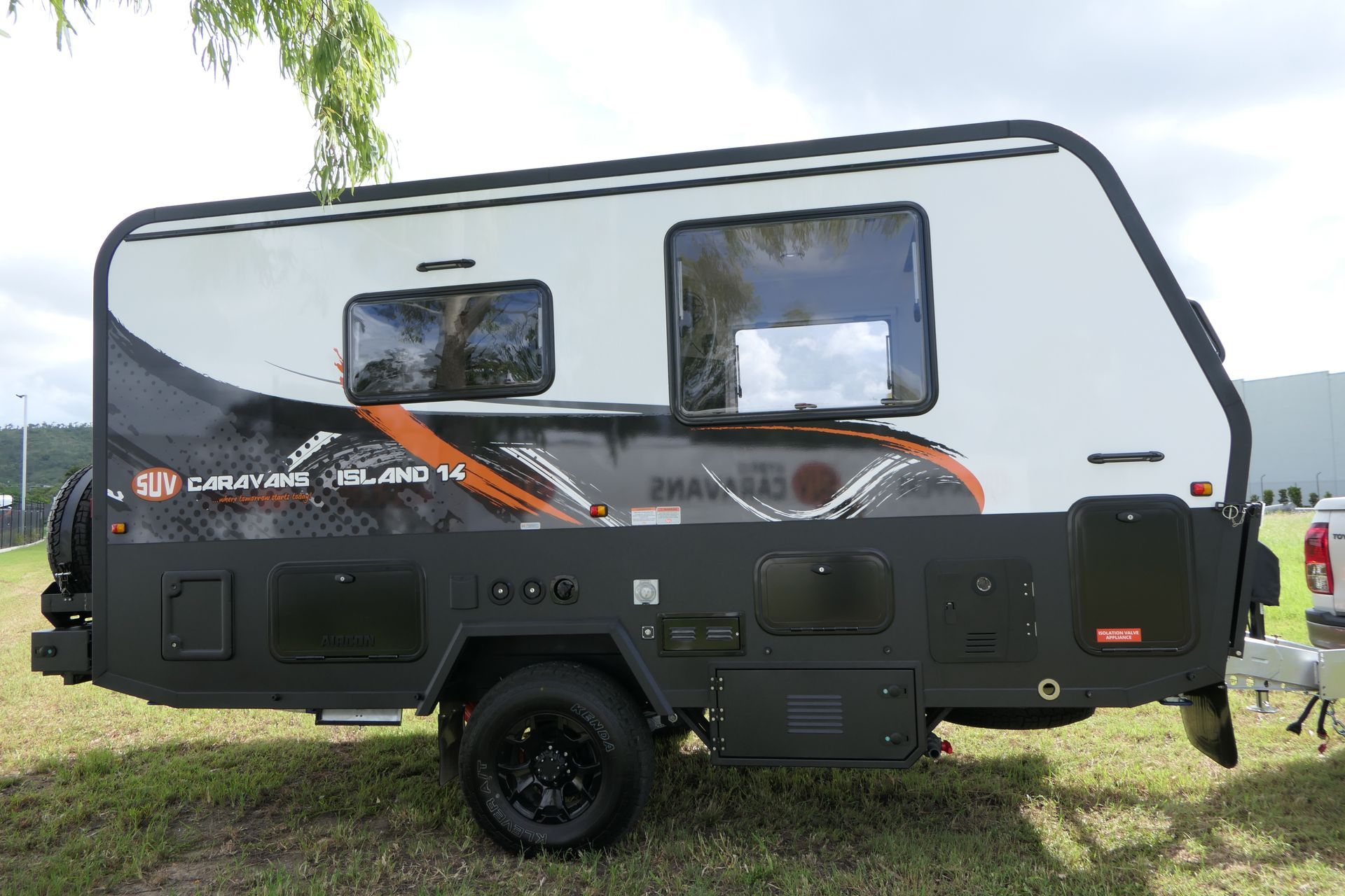 A camper trailer is parked in a grassy field next to a truck.