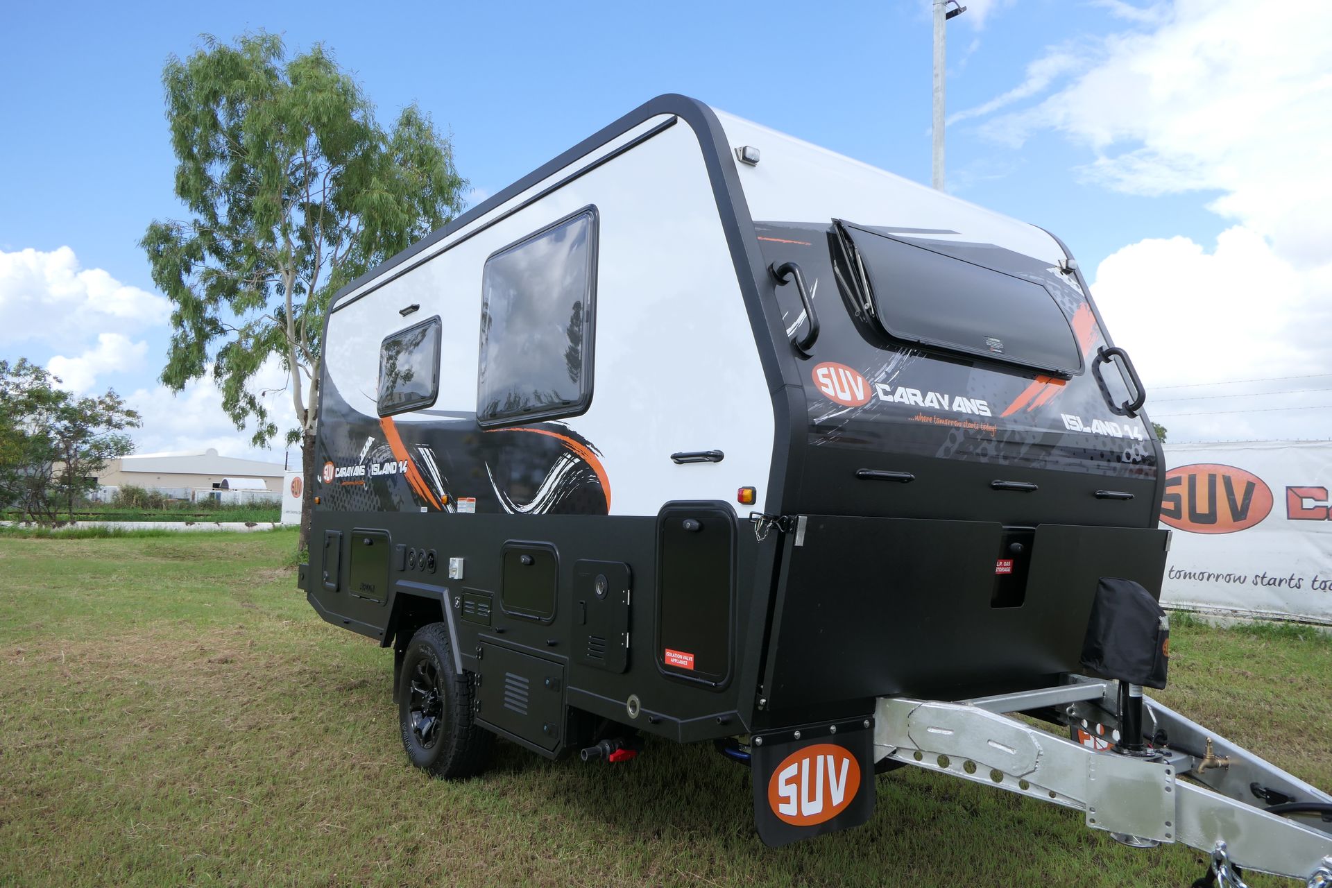 A white and black camper trailer is parked in a grassy field.