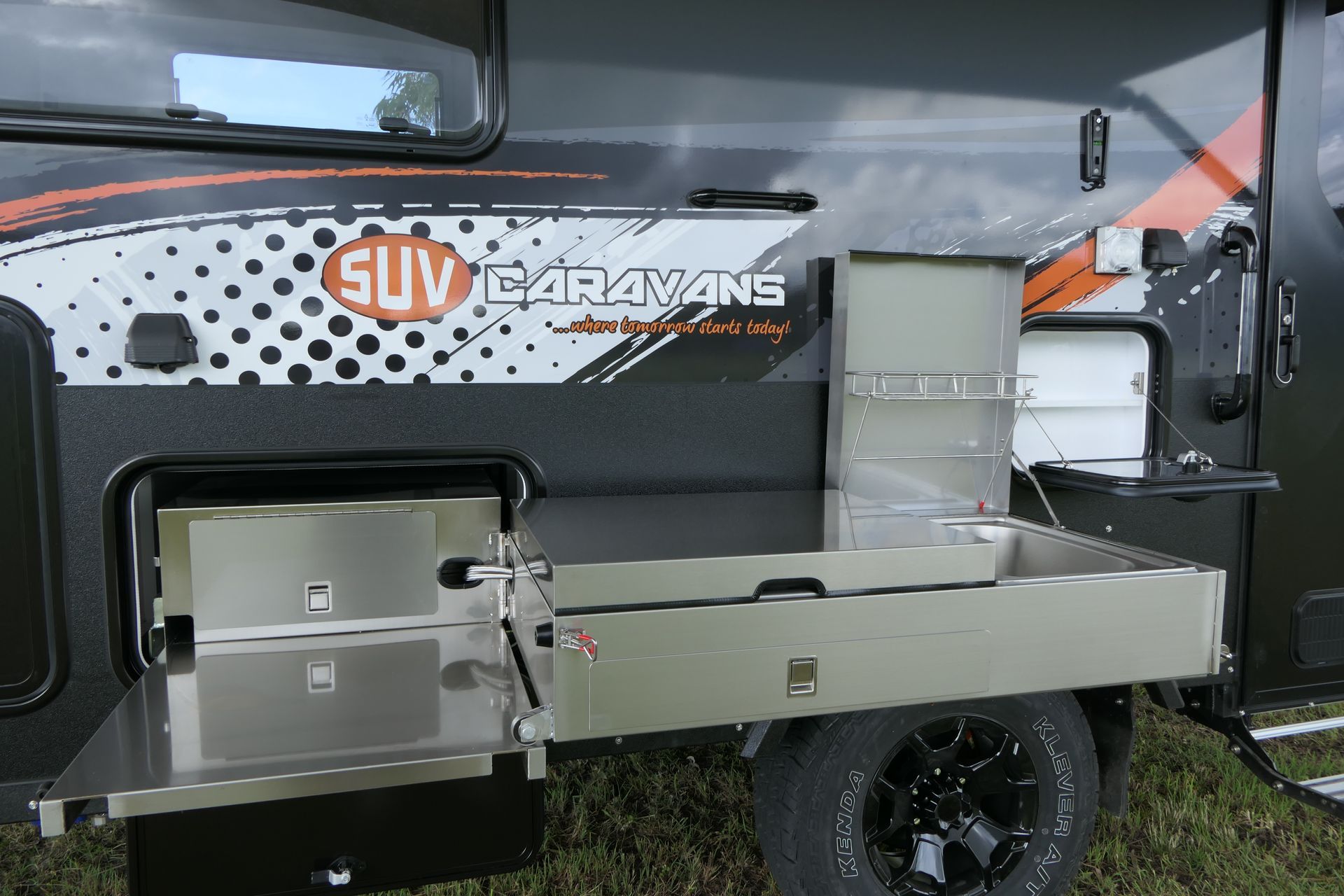 SUV caravan with an outdoor kitchen, featuring a pull-out cooking area and storage compartments.