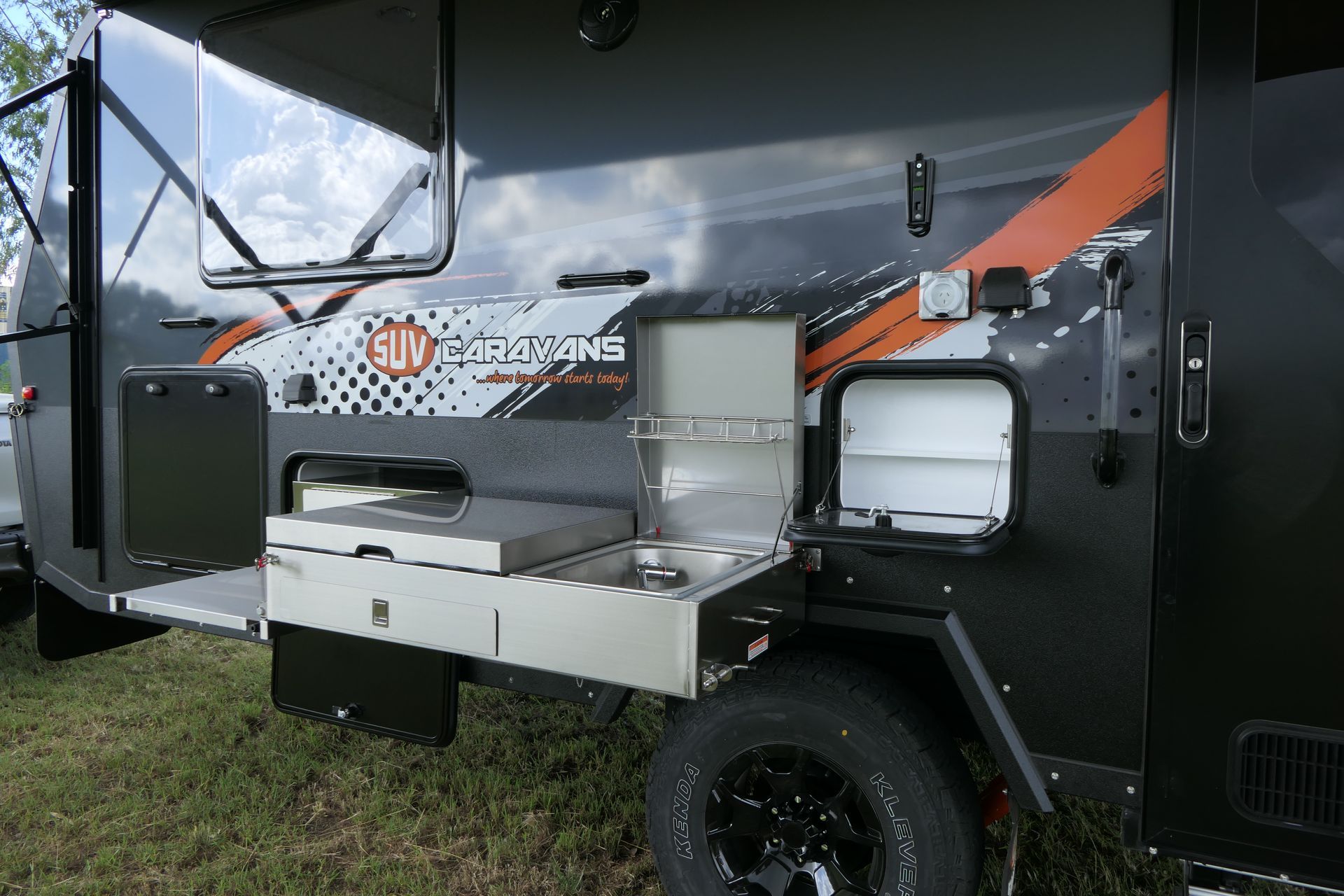 A camper trailer with a kitchen attached to the side of it.