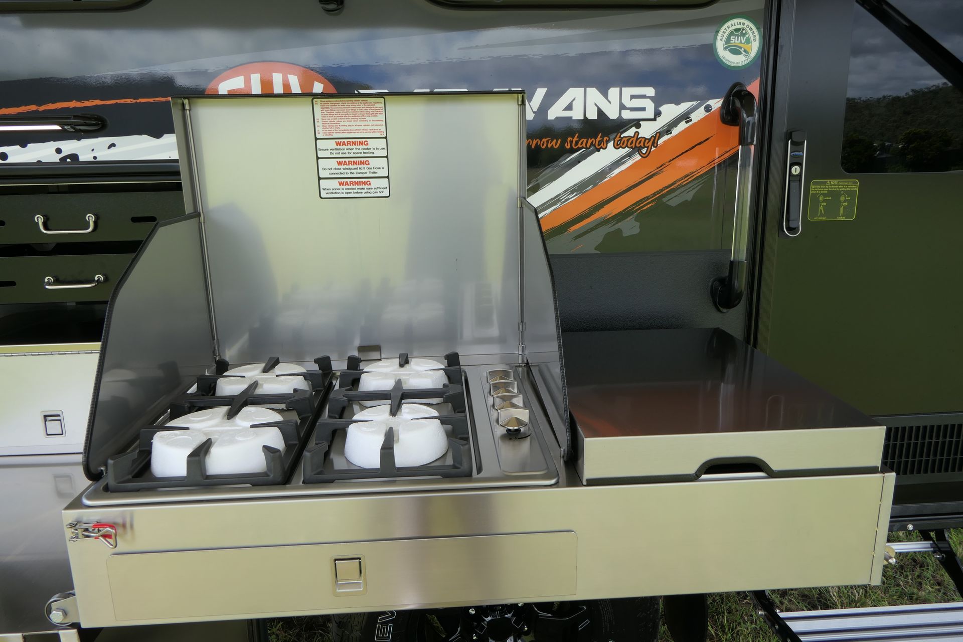 A vans trailer has a stove and a drawer underneath it