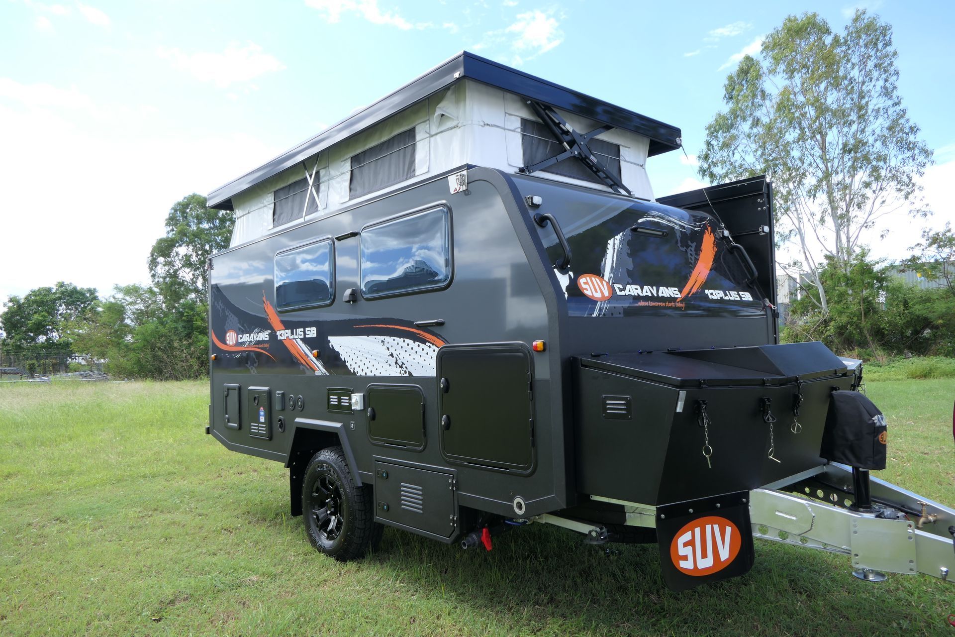 A camper trailer is parked in a grassy field.