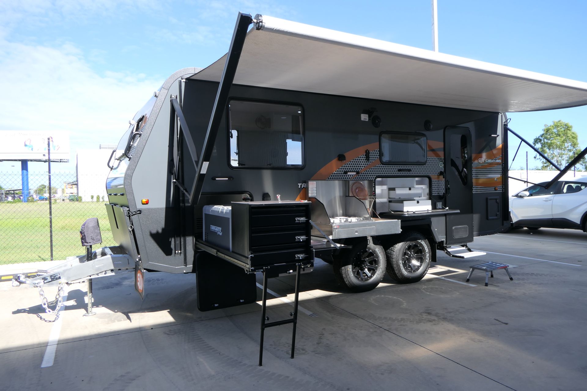 A trailer with a ladder attached to it is parked in a parking lot.